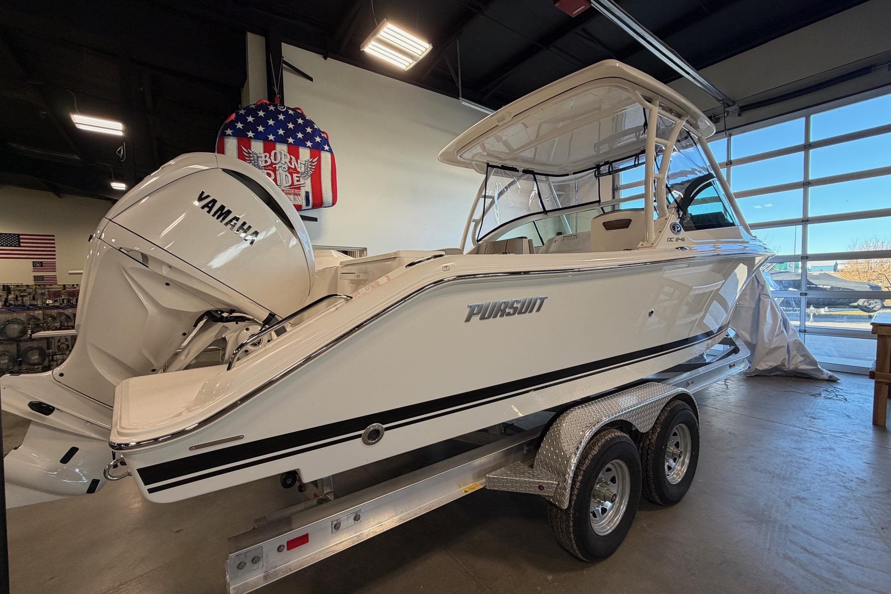 2026 Pursuit DC 246 Dual Console boat with Yamaha engine on trailer in showroom.