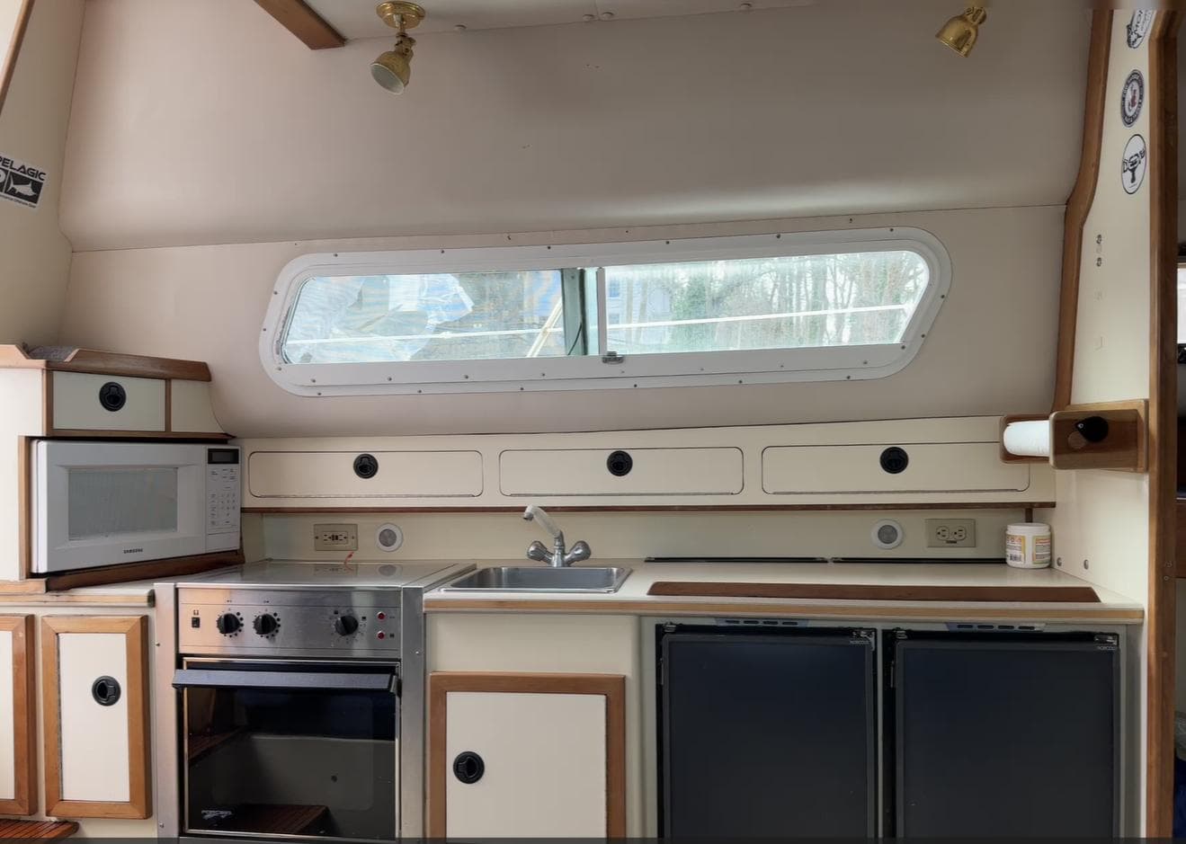Interior kitchen of a 2001 Albin 32+2 boat with stove, microwave, and sink.
