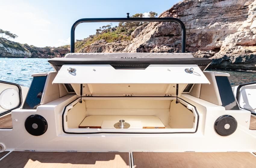 2025 Navan S30 boat storage compartment open, showcasing spacious interior against scenic rocky coastline.