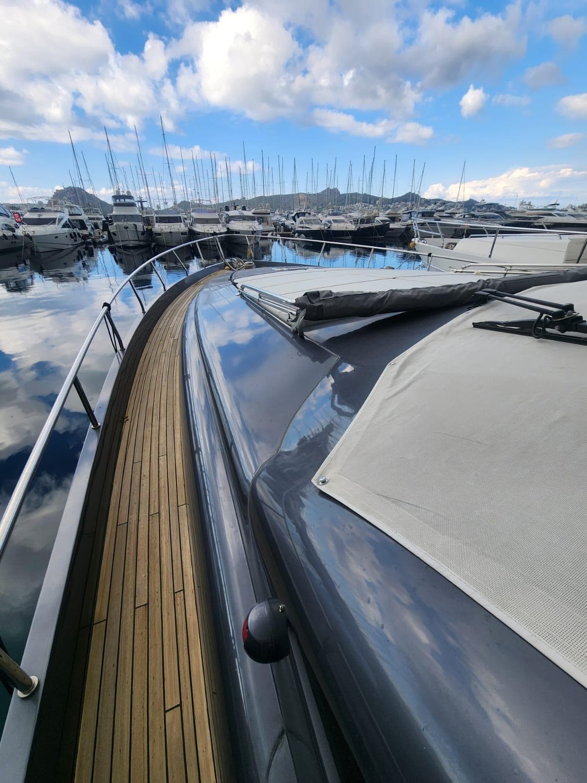 2011 Pershing 72 yacht docked in a marina, reflecting blue sky and clouds.