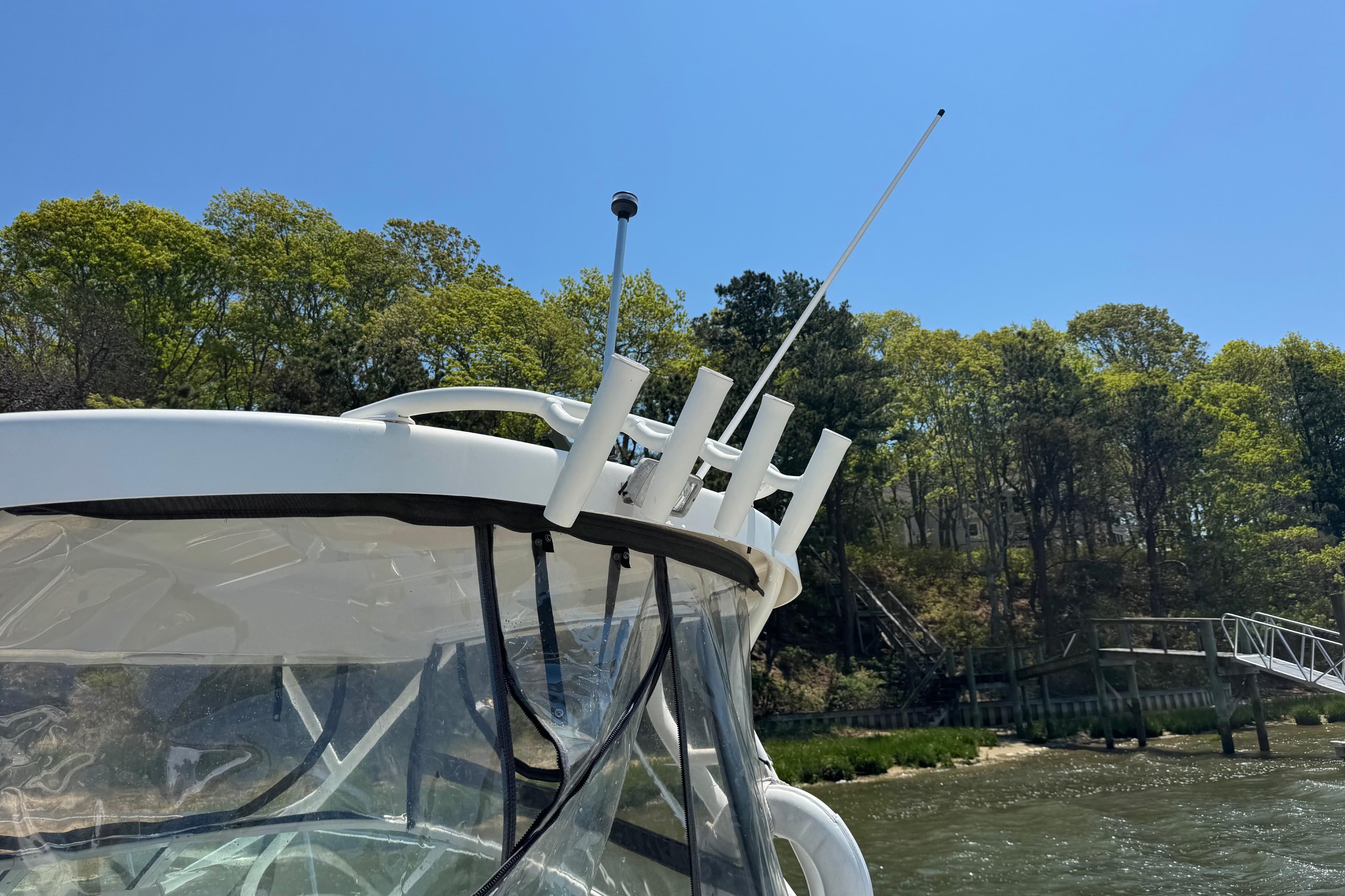 2016 Wellcraft 252 Coastal boat with antennas, cruising near a wooded shoreline.