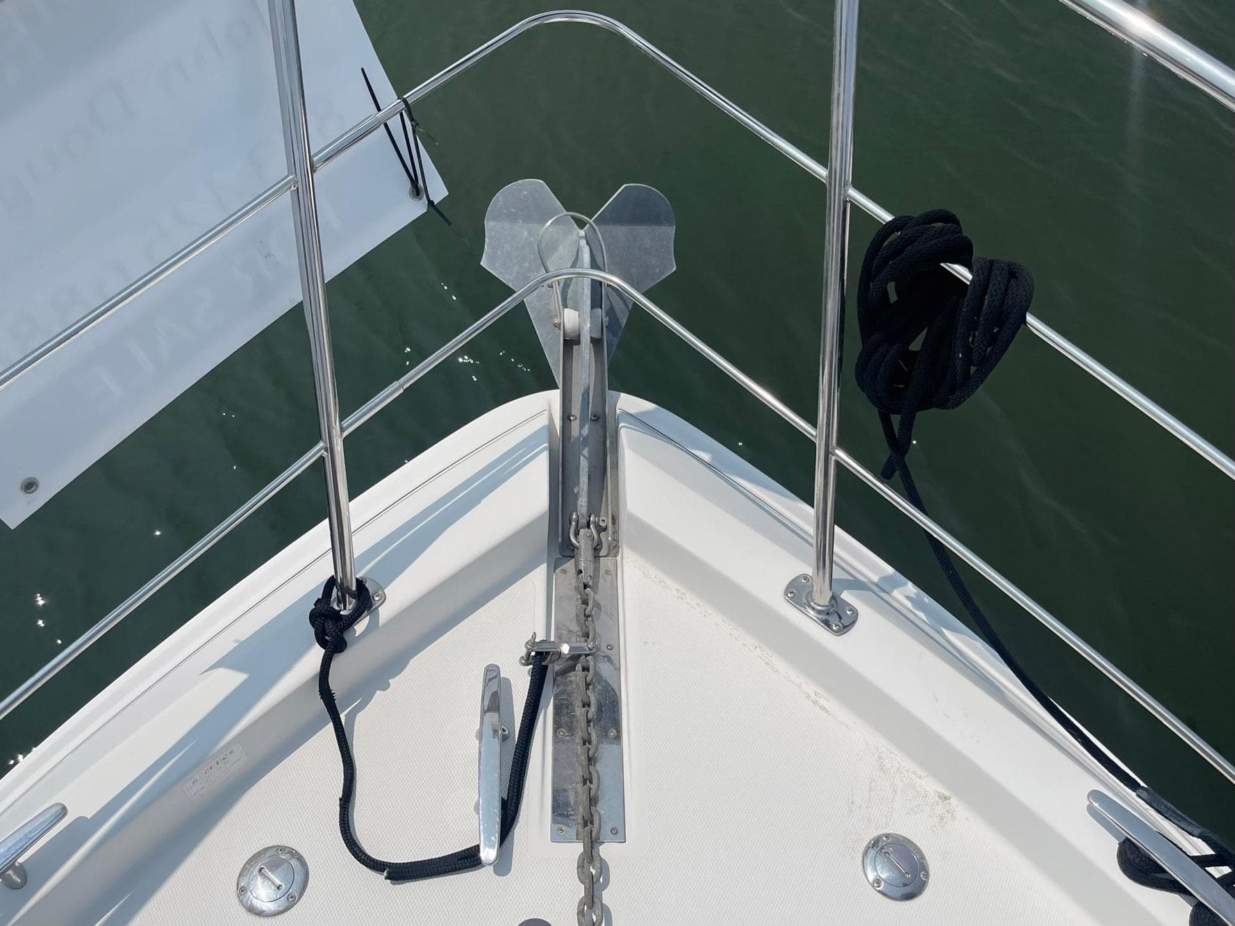Bow of 2006 Carver 36 Mariner with anchor and railing, docked on calm water.