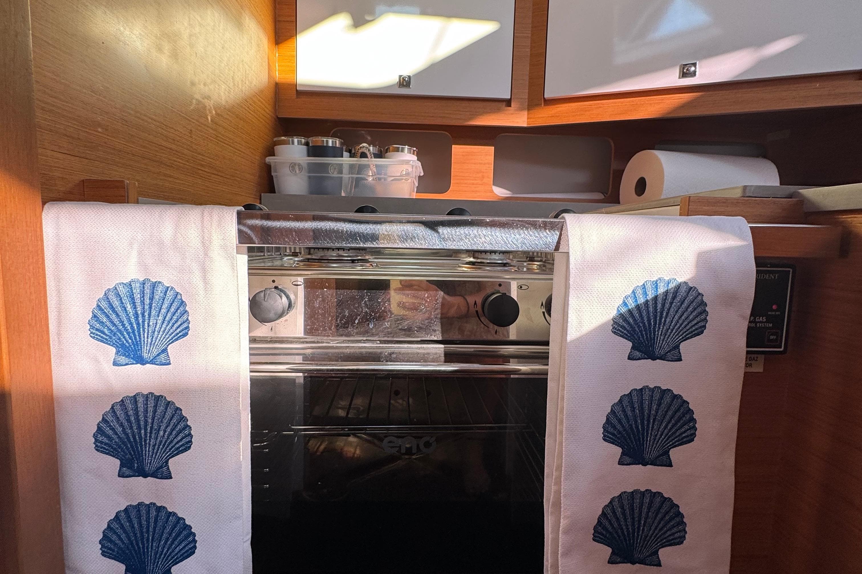 Cozy kitchen in 2023 Dufour 37 yacht with seashell-themed towels and modern appliances.