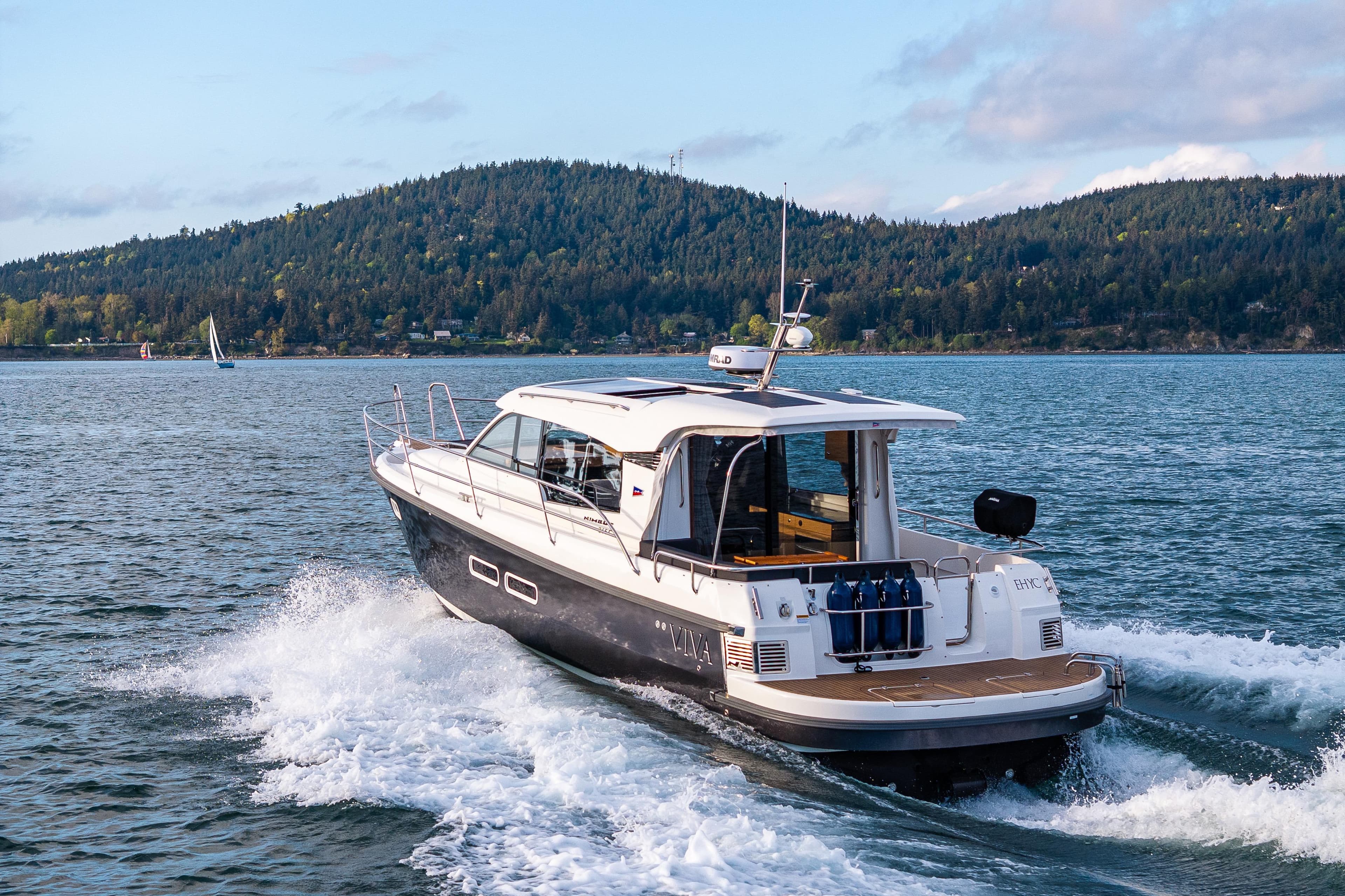Nimbus 365 Coupe 2022 cruising on a scenic lake with forested hills in the background.