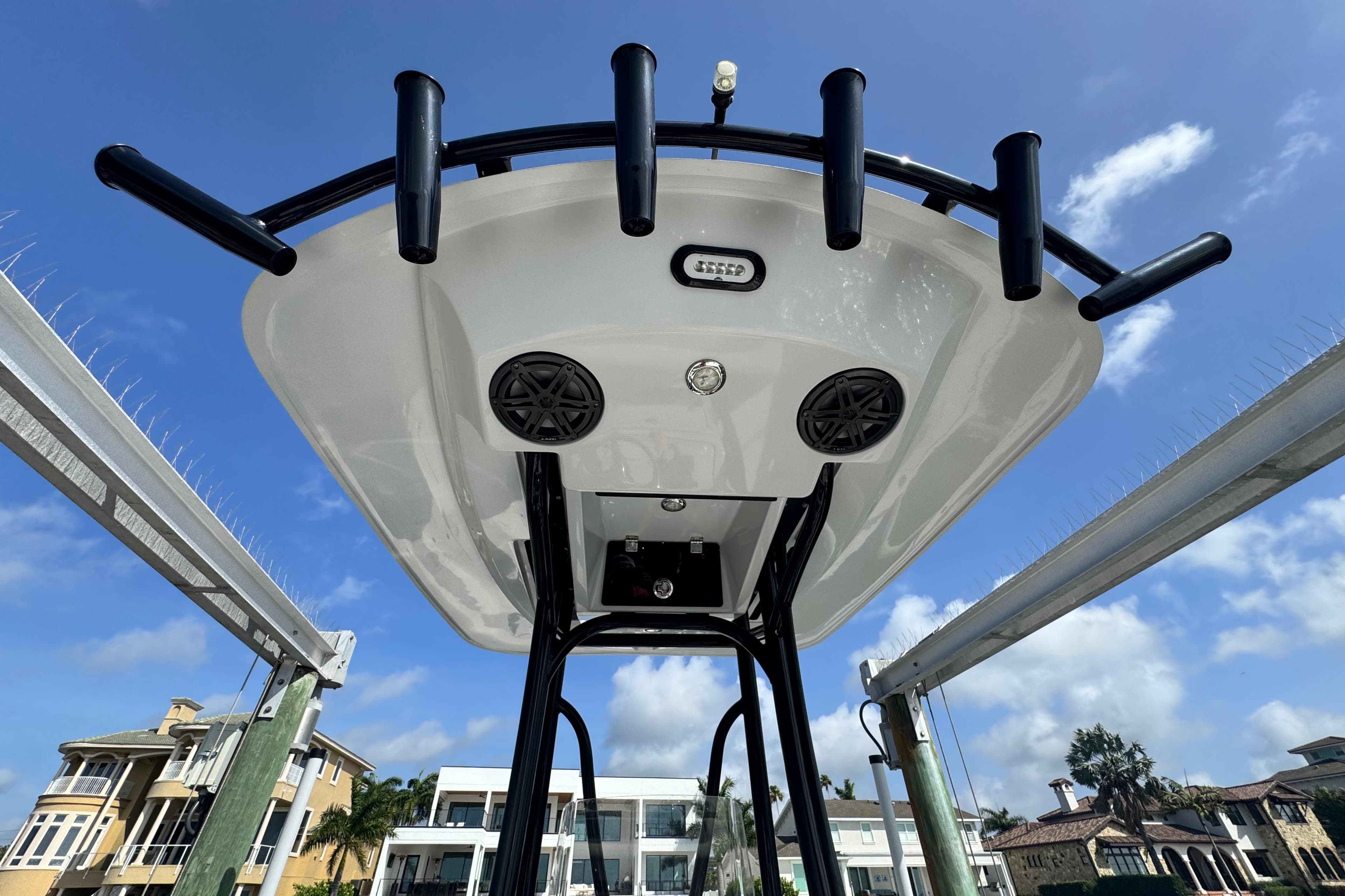 2022 Pathfinder 2400 TRS boat T-top with rod holders and speakers, under a clear blue sky.