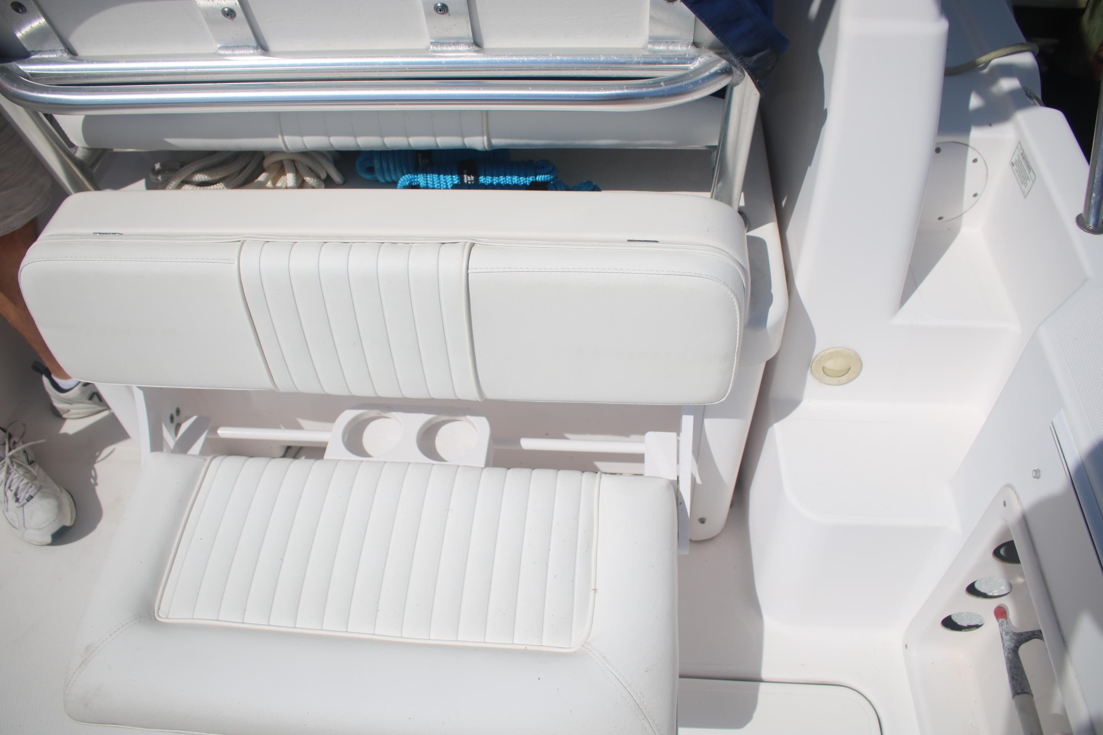 White seating area on a 2011 Larson Carbiro 240 boat, featuring storage and cup holders.