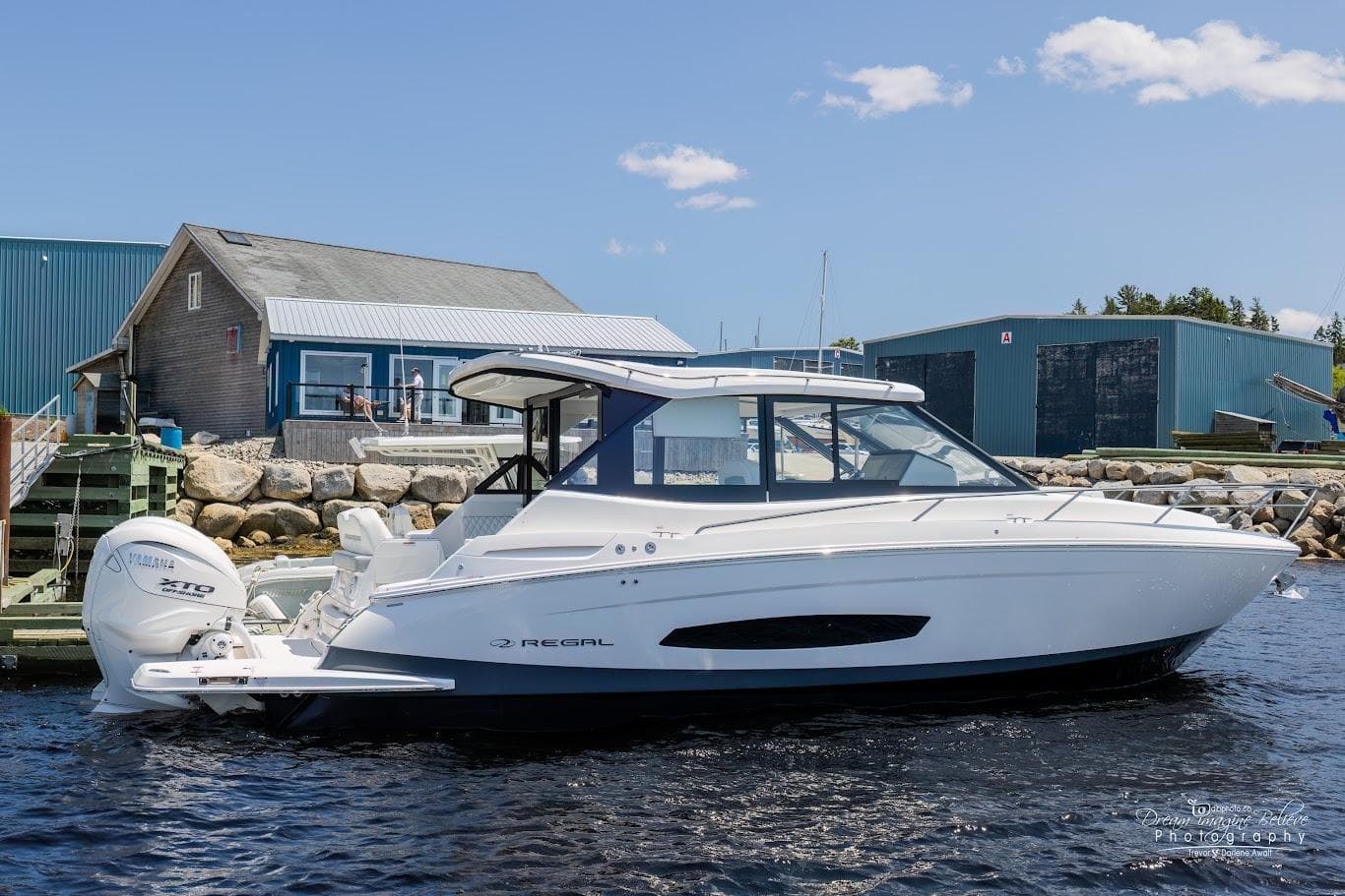 Regal 36 XO 2025 motorboat docked at harbor on a sunny day.