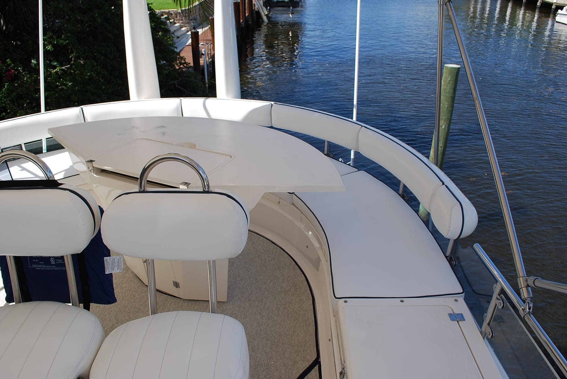 Luxury seating area on a 2000 Fairline Squadron yacht, overlooking a serene waterfront.