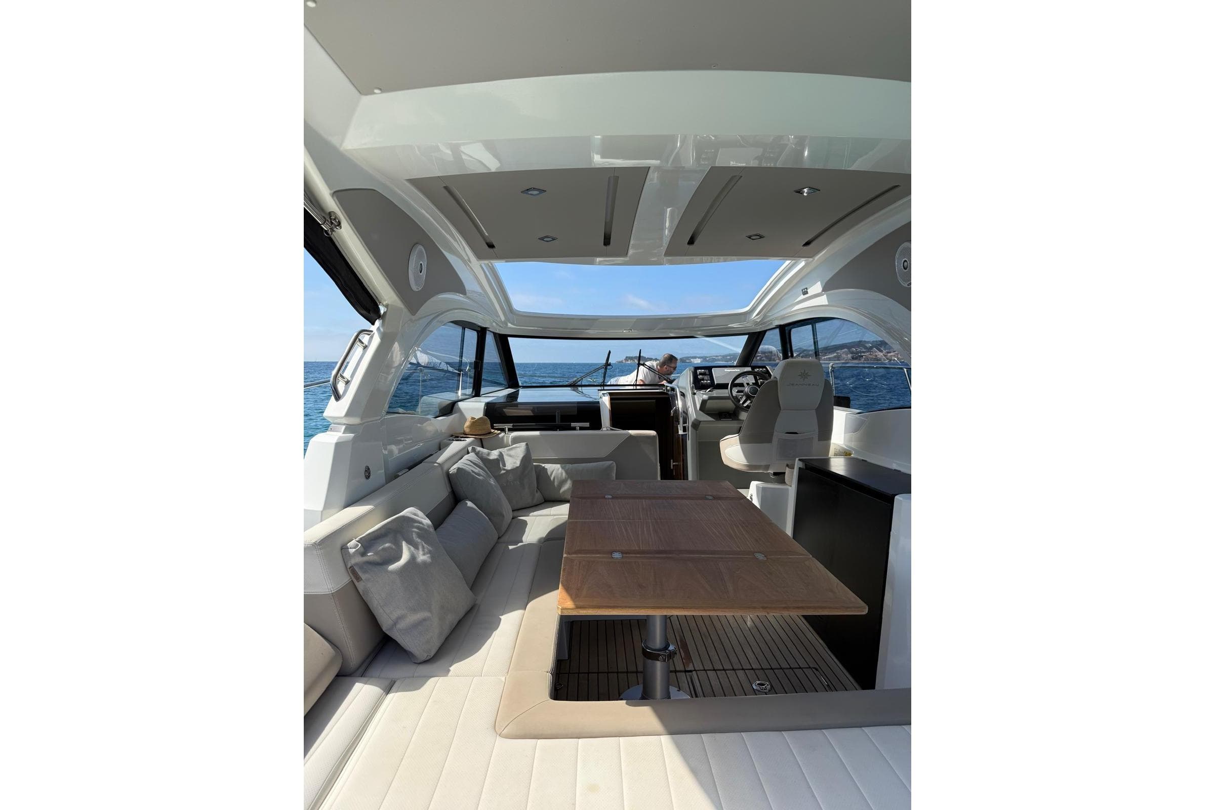 Interior of 2017 Jeanneau Leader 33 yacht with seating and table, cruising on open water.