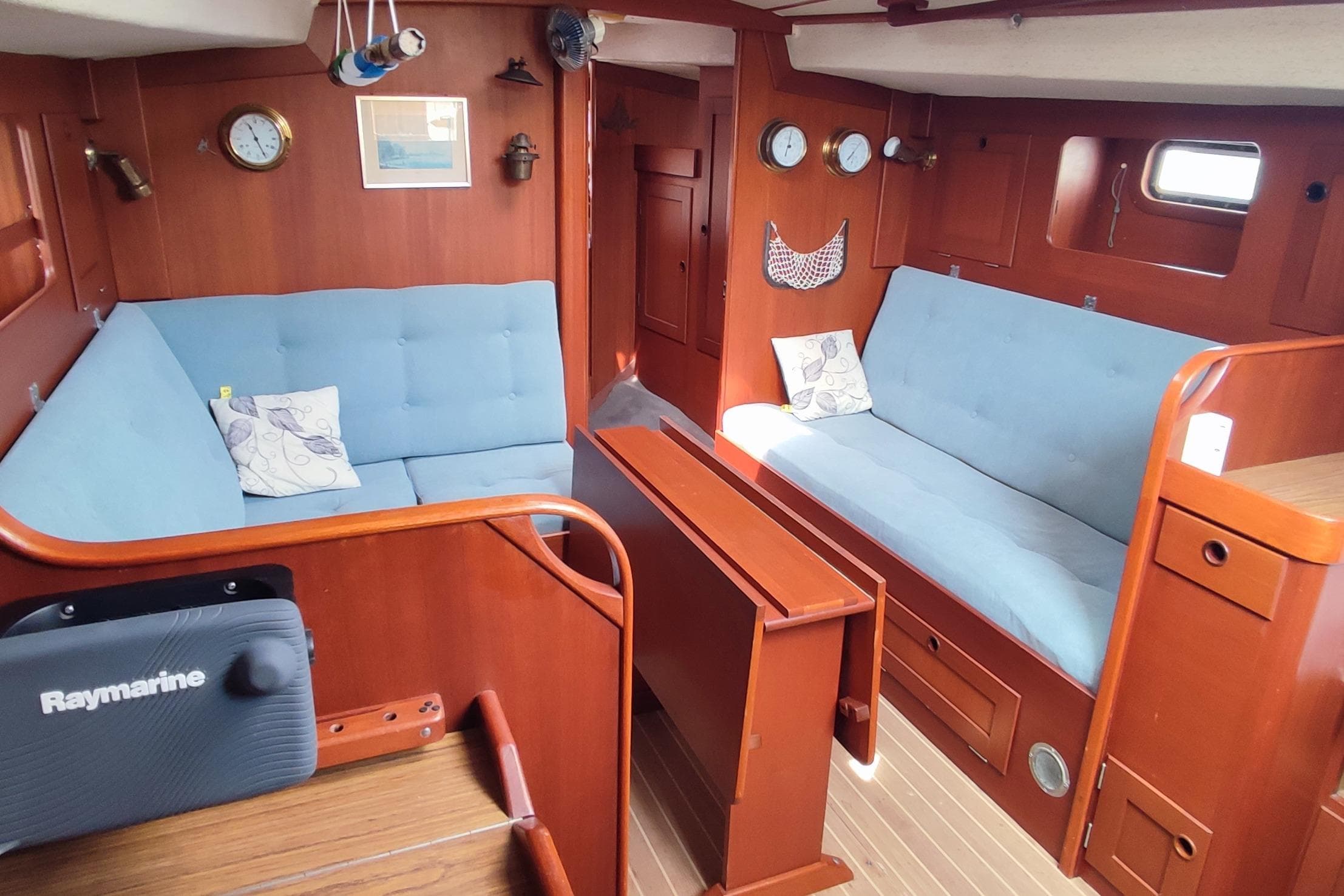 Interior of 1982 Hallberg-Rassy 352 yacht with blue cushioned seating and wooden finishes.