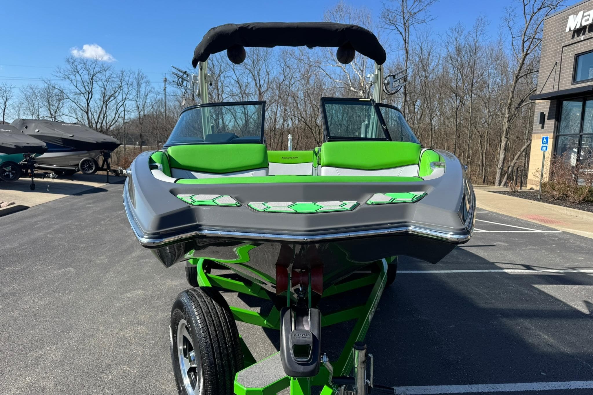 2015 MasterCraft NXT20 boat with green accents on a trailer in a parking lot.