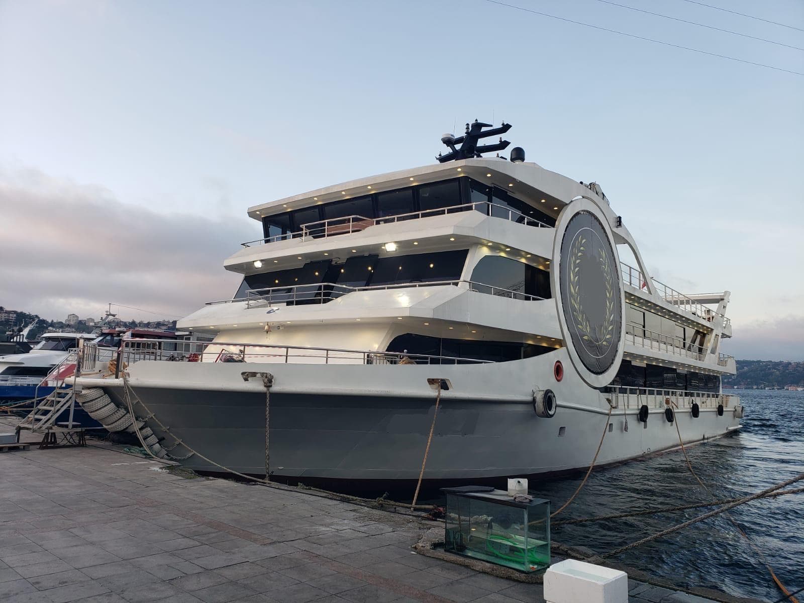 Modern Custom-Craft restaurant and excursion vessel docked, 2025 model, with sleek design and multiple decks.