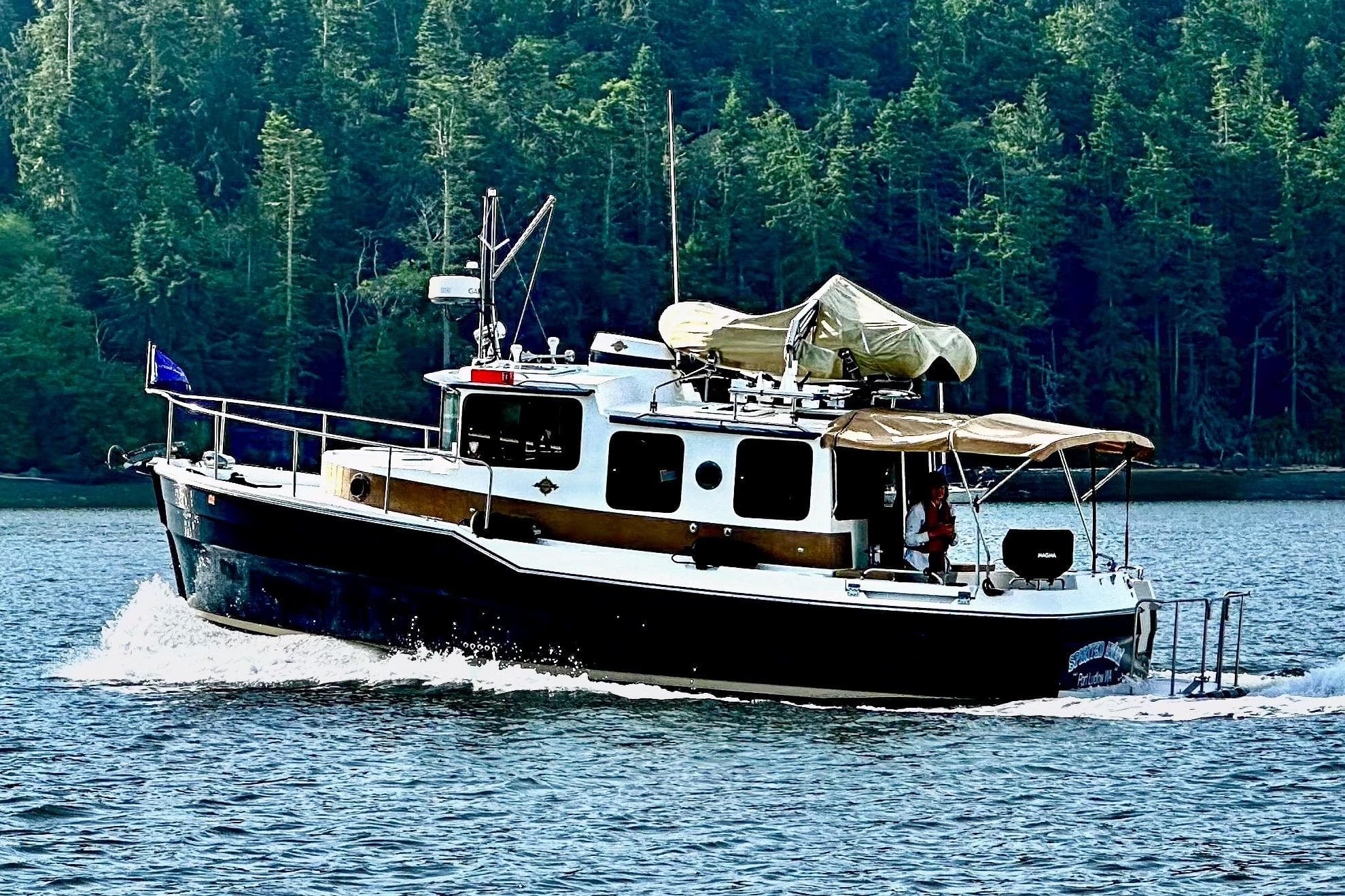 2010 Ranger Tugs R-29 cruising on a serene lake with forested backdrop.