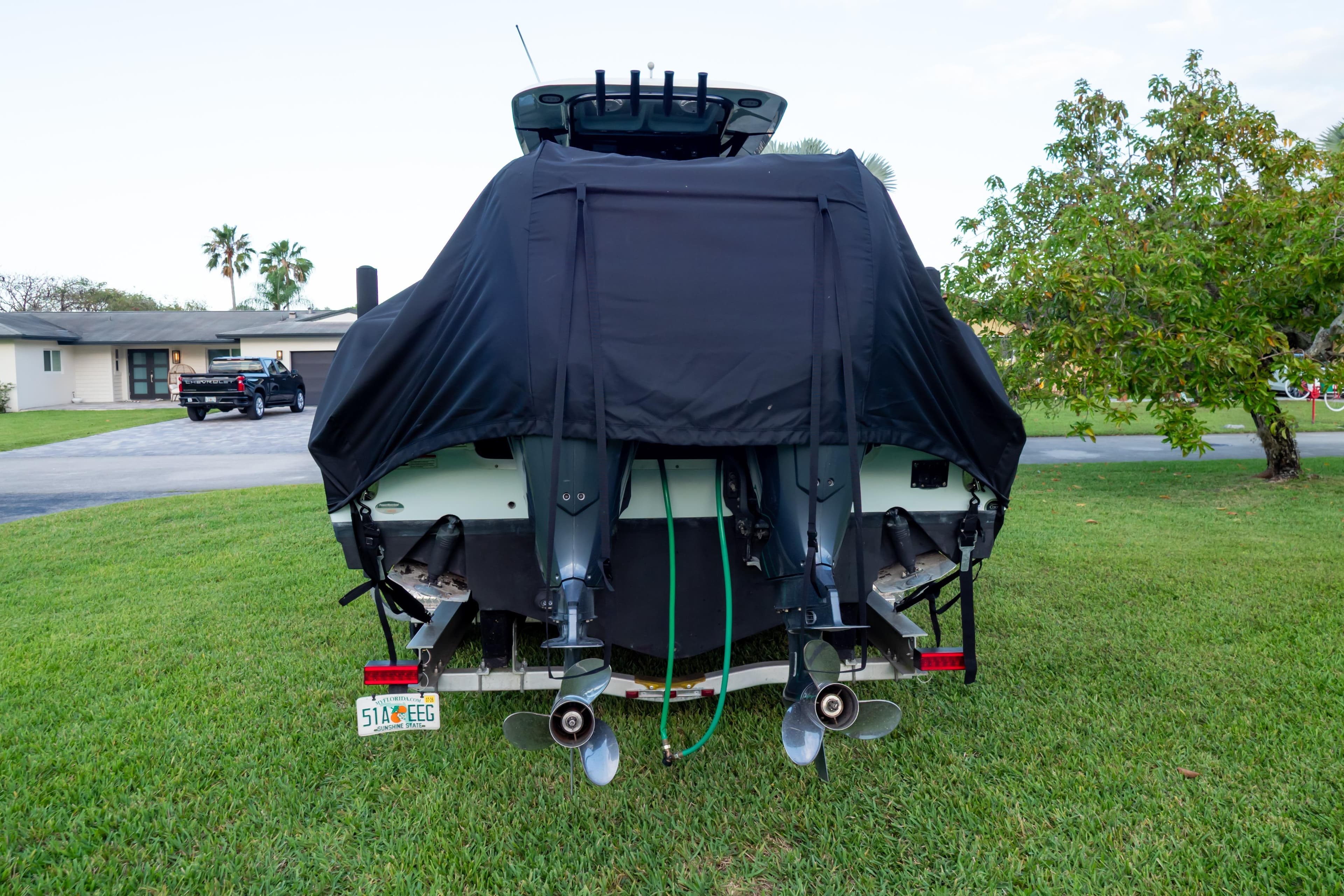 2021 Sea Hunt Gamefish 27 boat with cover, parked on grass, rear view.