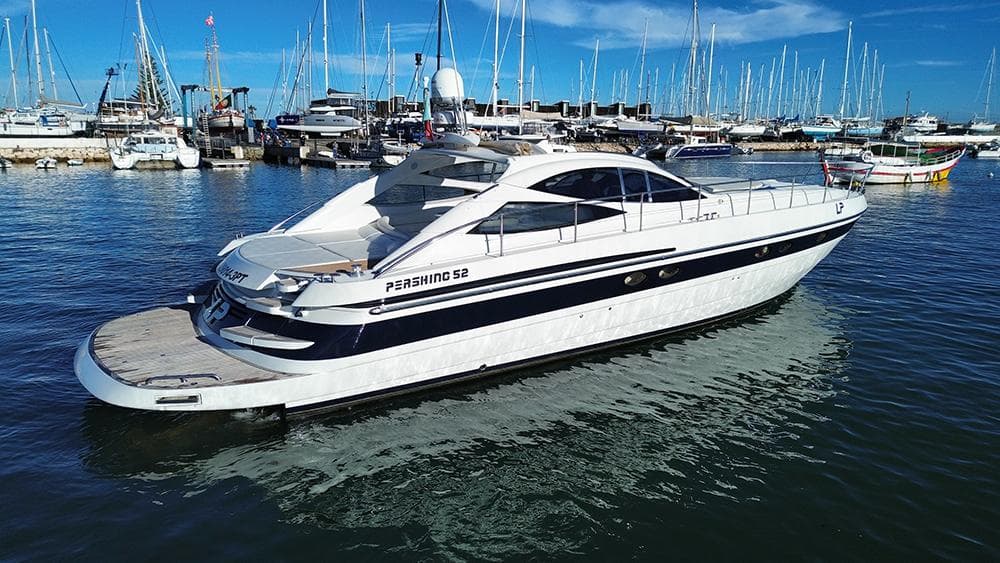 2001 Pershing 52 yacht docked in a marina, surrounded by sailboats under a clear blue sky.