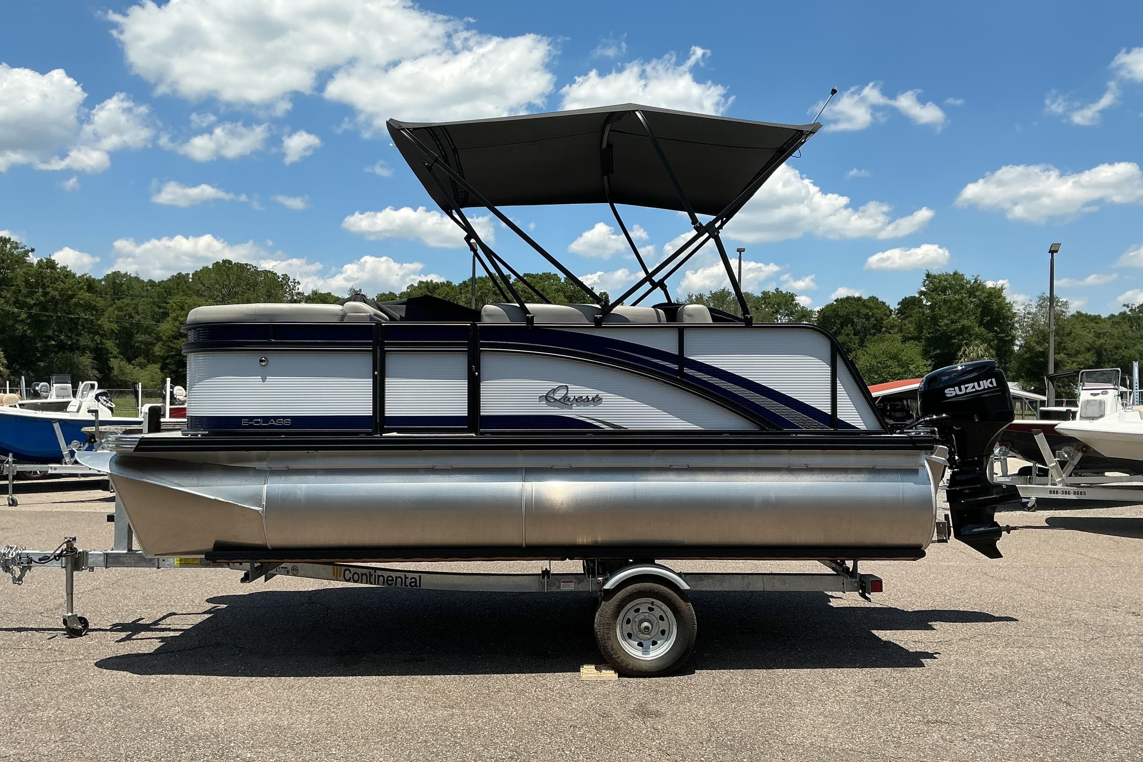 2026 Qwest Lanai 816 pontoon boat with canopy, parked on trailer under blue sky.