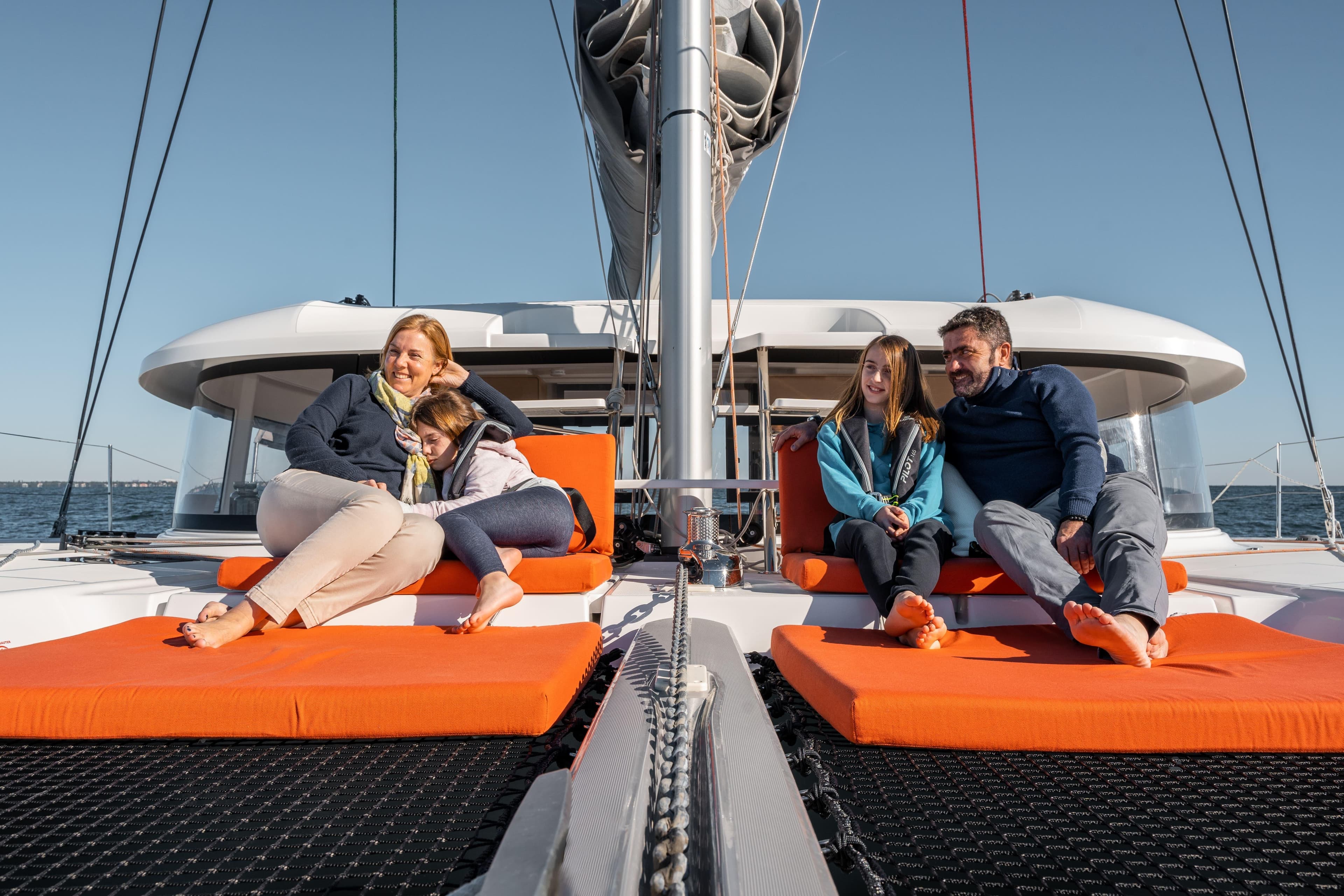 Family relaxing on a 2026 Excess 14 catamaran, enjoying a sunny day at sea.