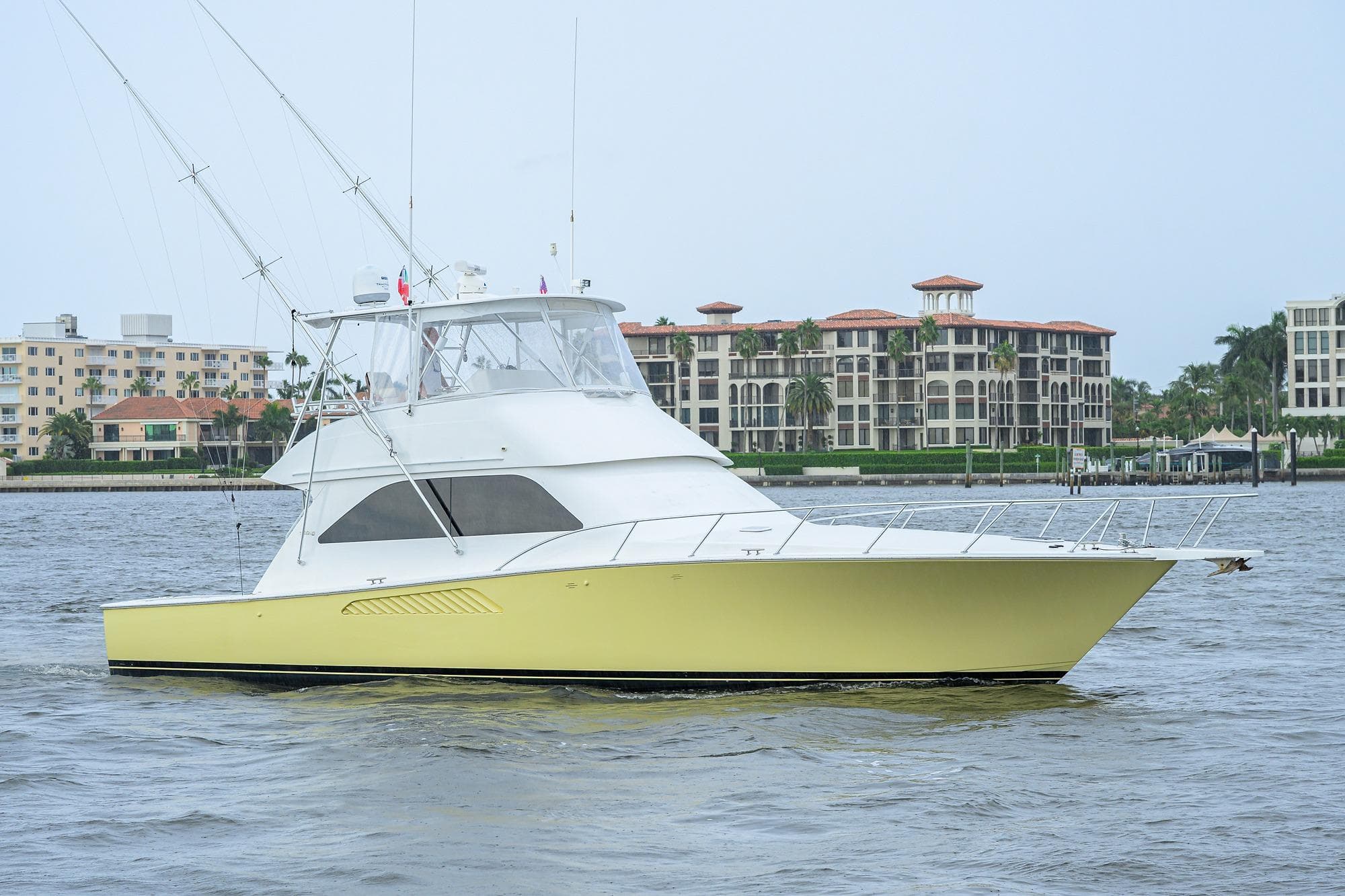 2004 Viking 48 Convertible yacht cruising near waterfront buildings.
