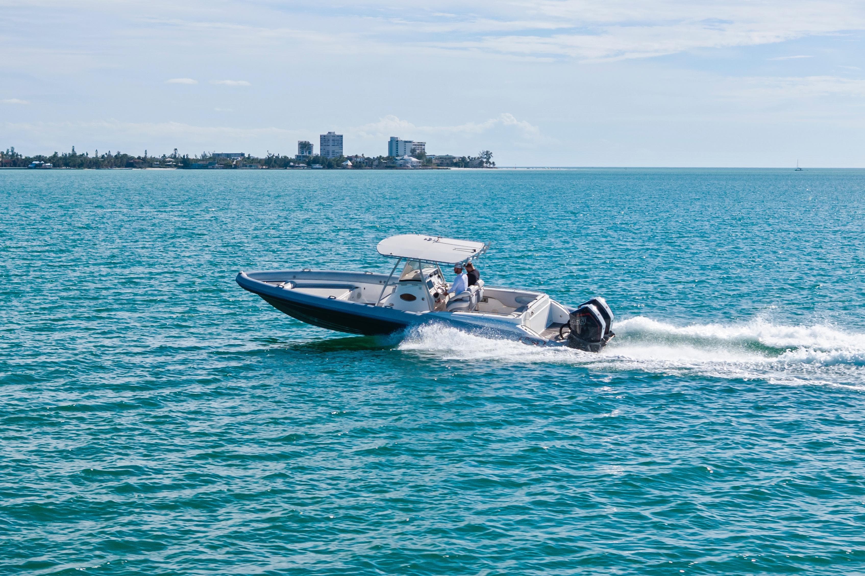 A 2014 Airship 330 boat cruising on clear blue water near a distant shoreline.