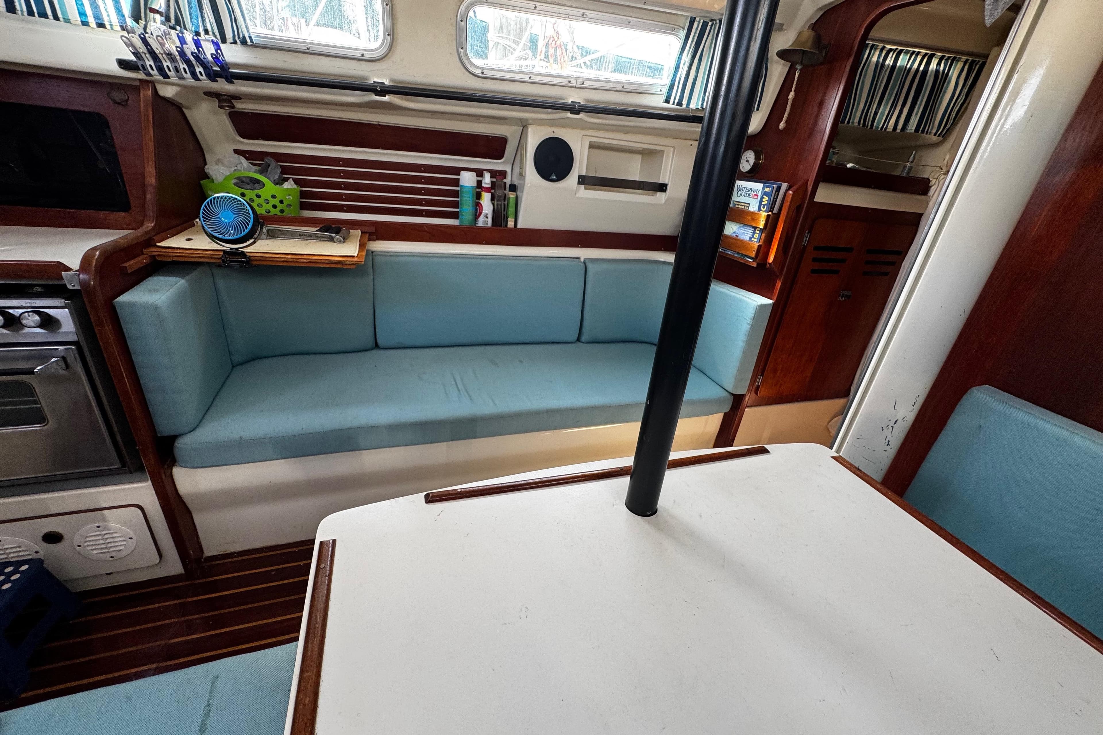 Interior of 1982 Pearson 323 sailboat with blue seating and wooden accents.