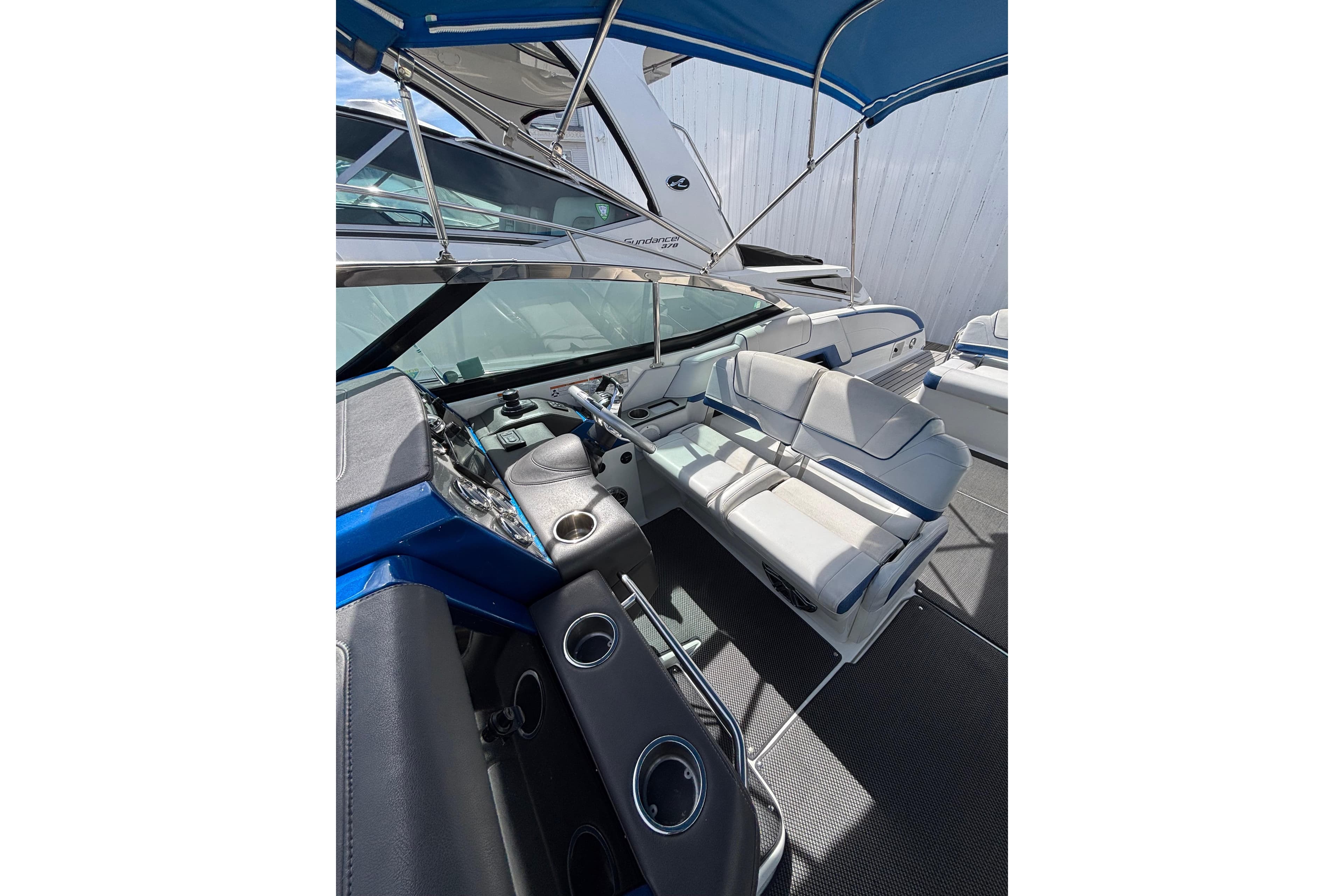 2018 Formula 330 Crossover Bowrider I/O interior with seating and helm under blue canopy.