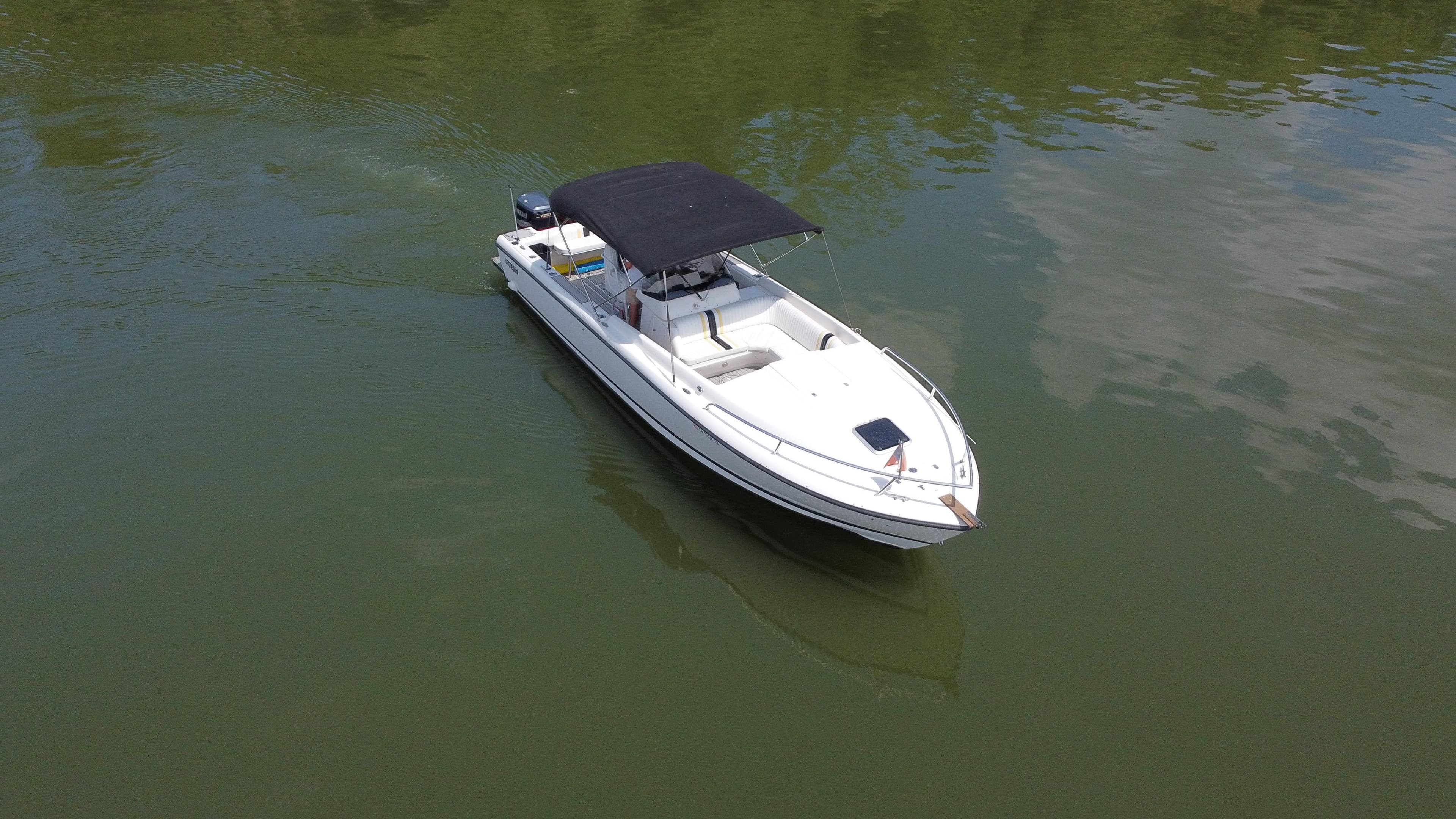 2002 Intrepid 323 Cuddy boat with black canopy on calm water.