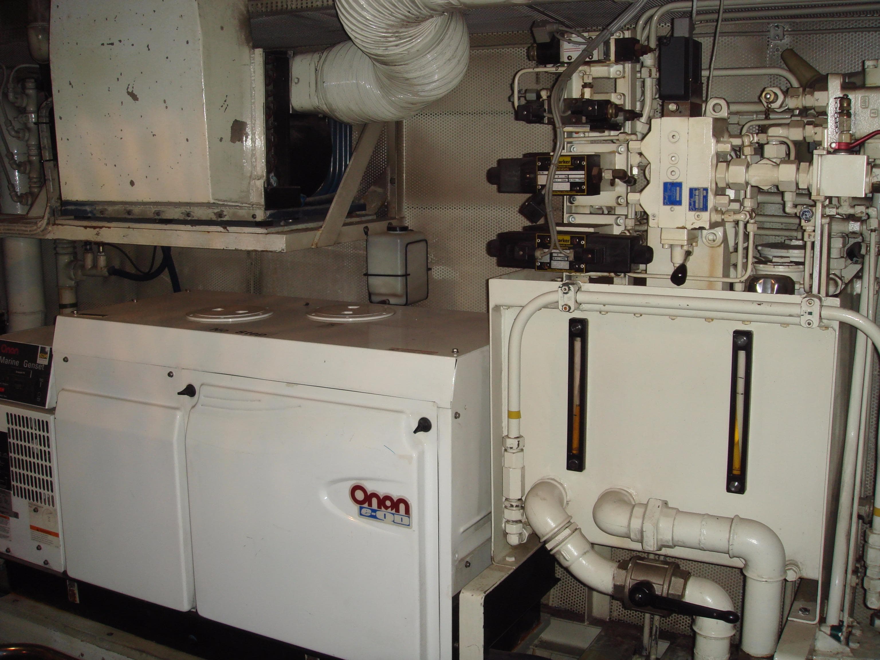 Engine room of a 1987 Moonen 72 yacht featuring Onan generator and complex piping system.