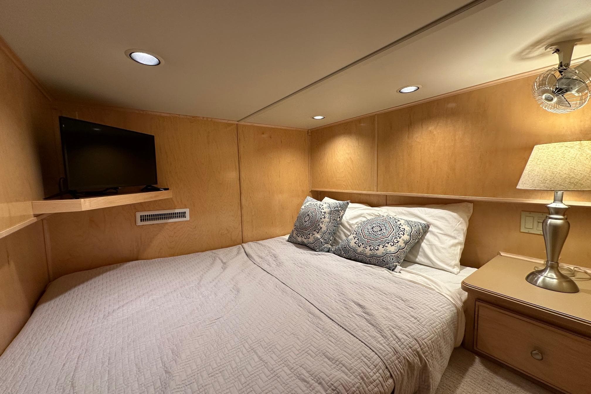 Cozy bedroom in 2003 Sumerset 18x80 houseboat with TV, lamp, and decorative pillows.