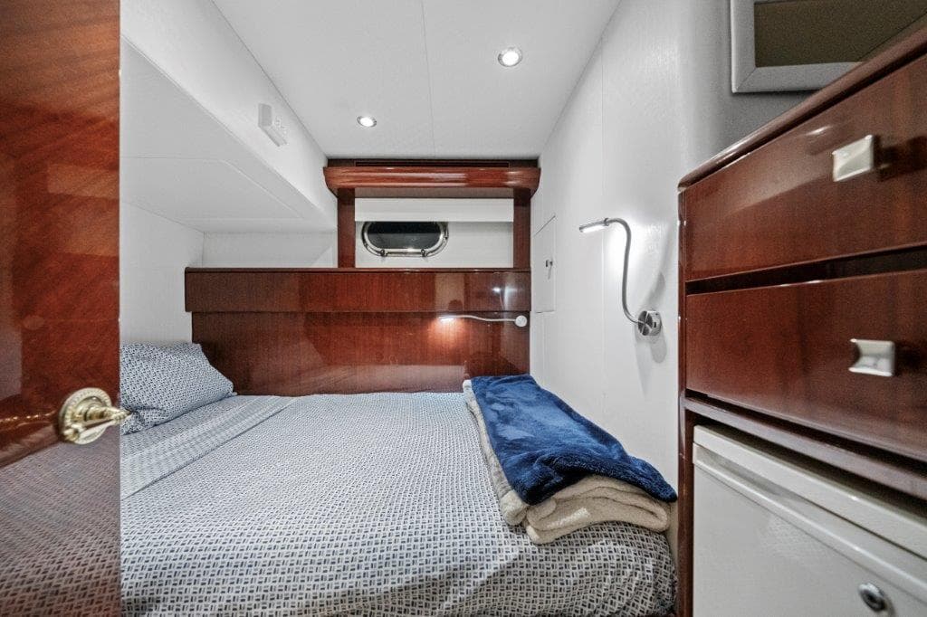 Luxurious 2006 Cheoy Lee Motor Yacht bedroom with elegant wood finishes and cozy bedding.