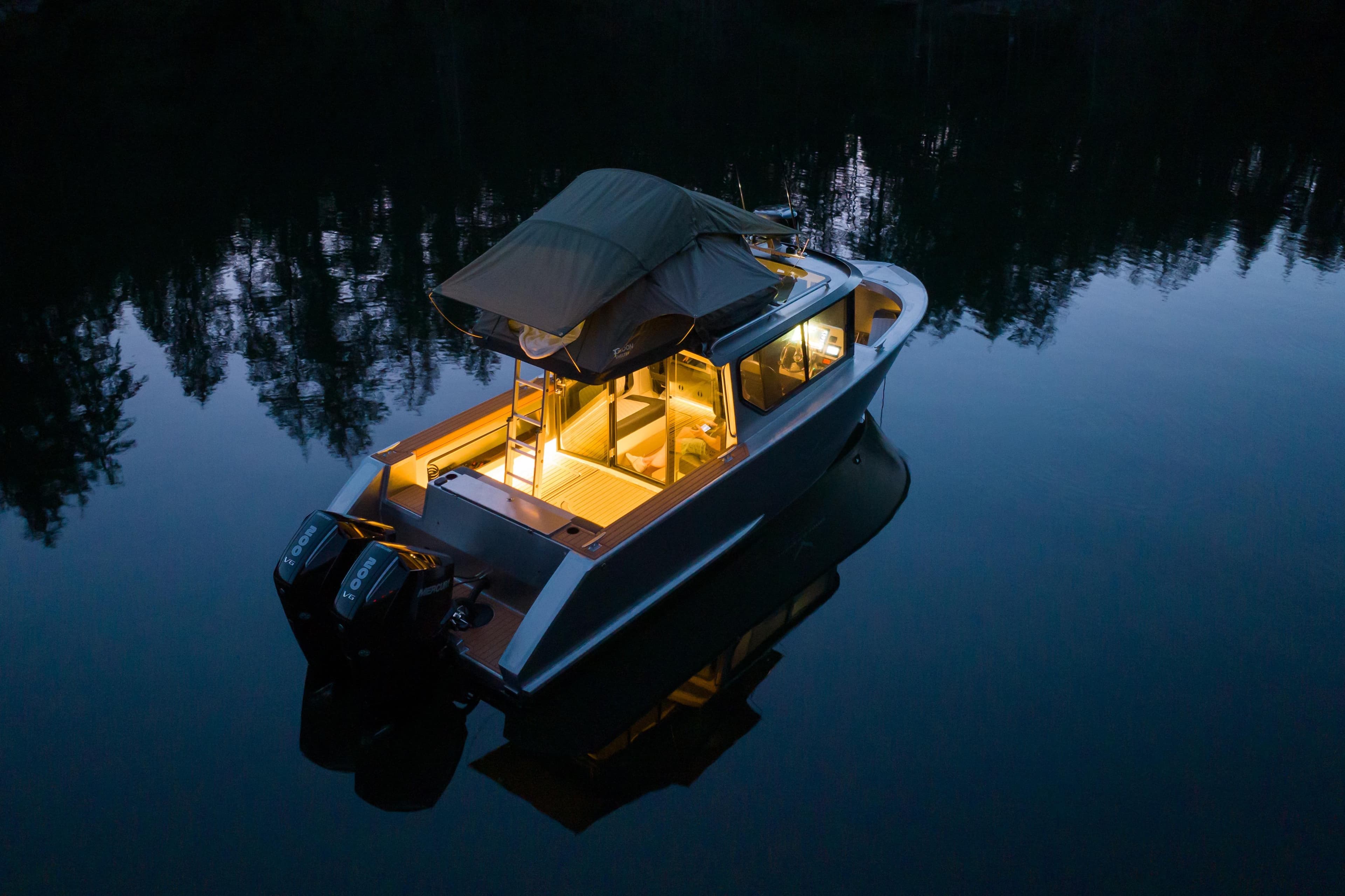 2026 Jasper Marine Defender 22 boat illuminated on calm water at dusk.