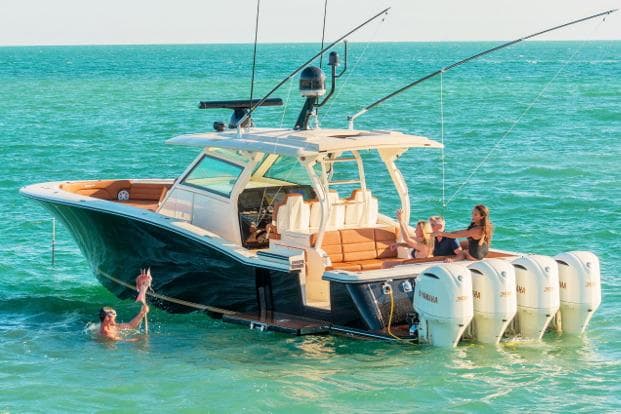 Manufacturer Provided Image: 2017 Scout 420 LXF boat with people relaxing and swimming in the ocean.