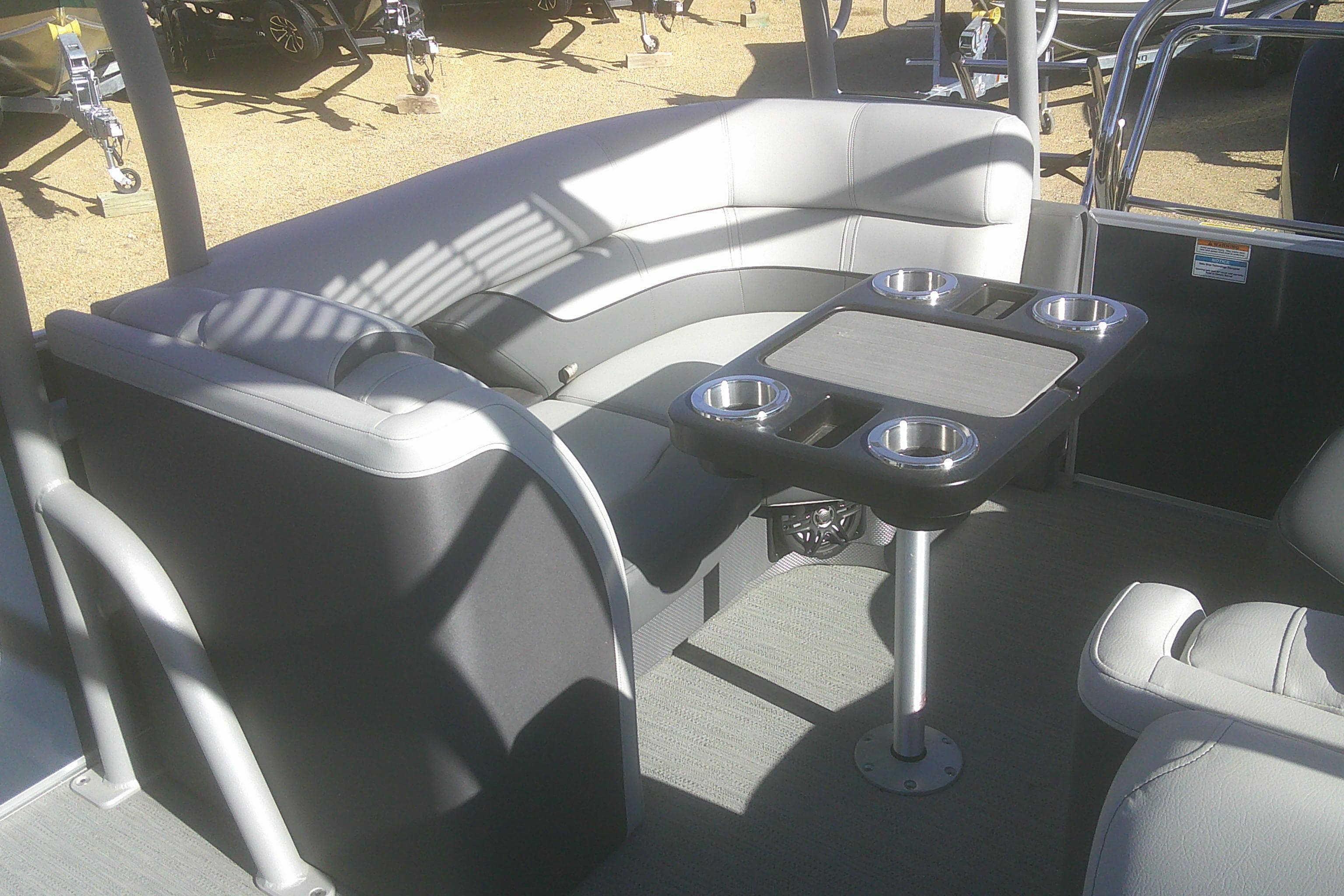 2024 Godfrey Monaco 255 SD boat interior with gray seating and cupholder table.