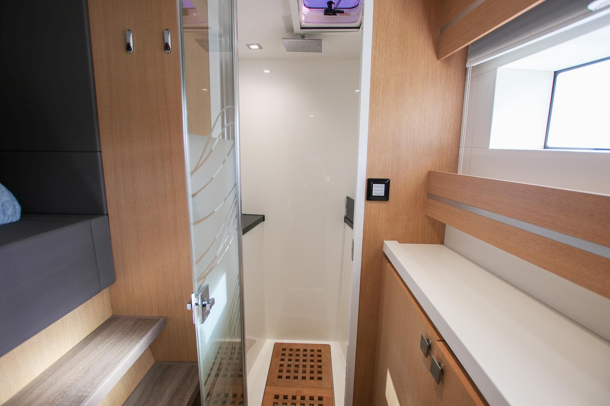 Modern bathroom interior on 2022 Privilege 510 yacht, featuring sleek wood finishes and glass door.