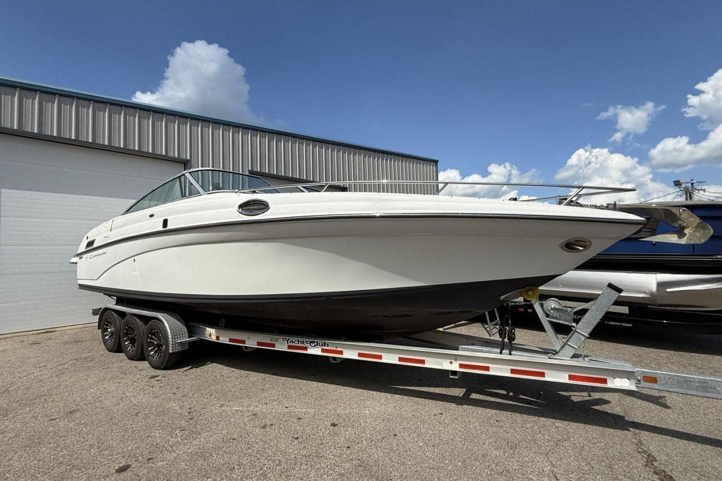 2005 Crownline 288 BR boat on trailer, parked outdoors under blue sky.