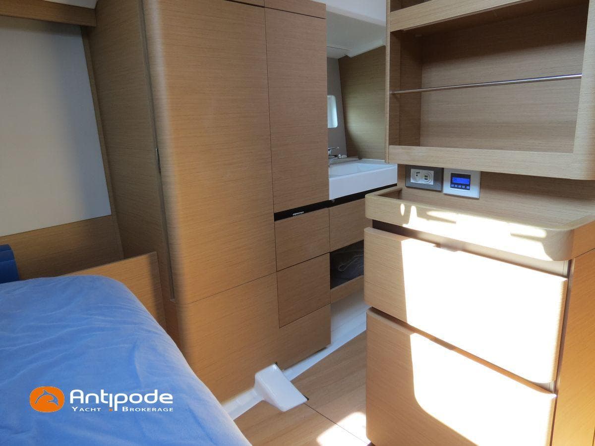 Interior of 2022 Jeanneau Sun Odyssey 490 yacht, featuring modern wood cabinetry and cozy sleeping area.