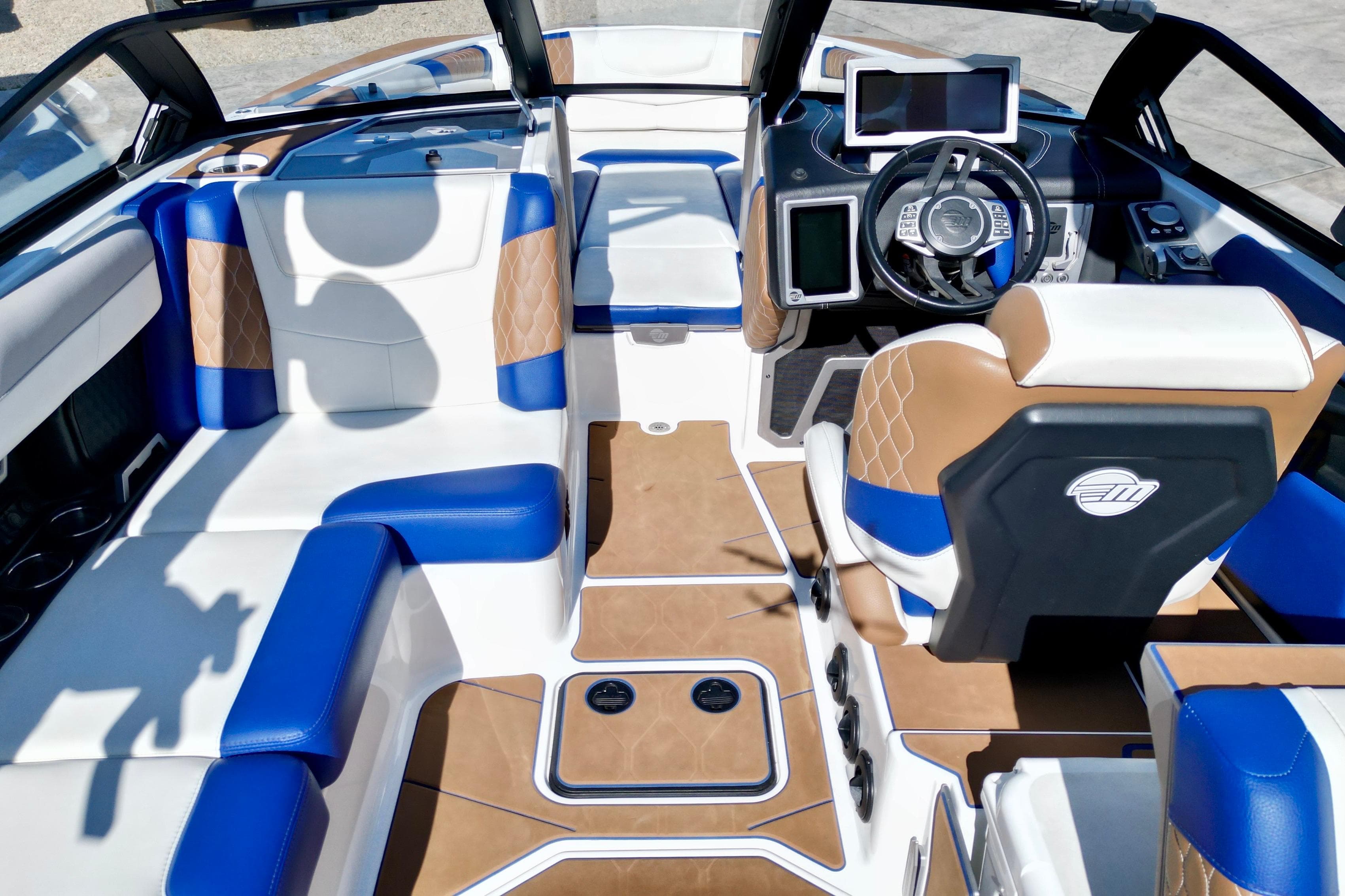 2022 Malibu M240 boat interior with blue and tan seating, modern dashboard, and steering wheel.