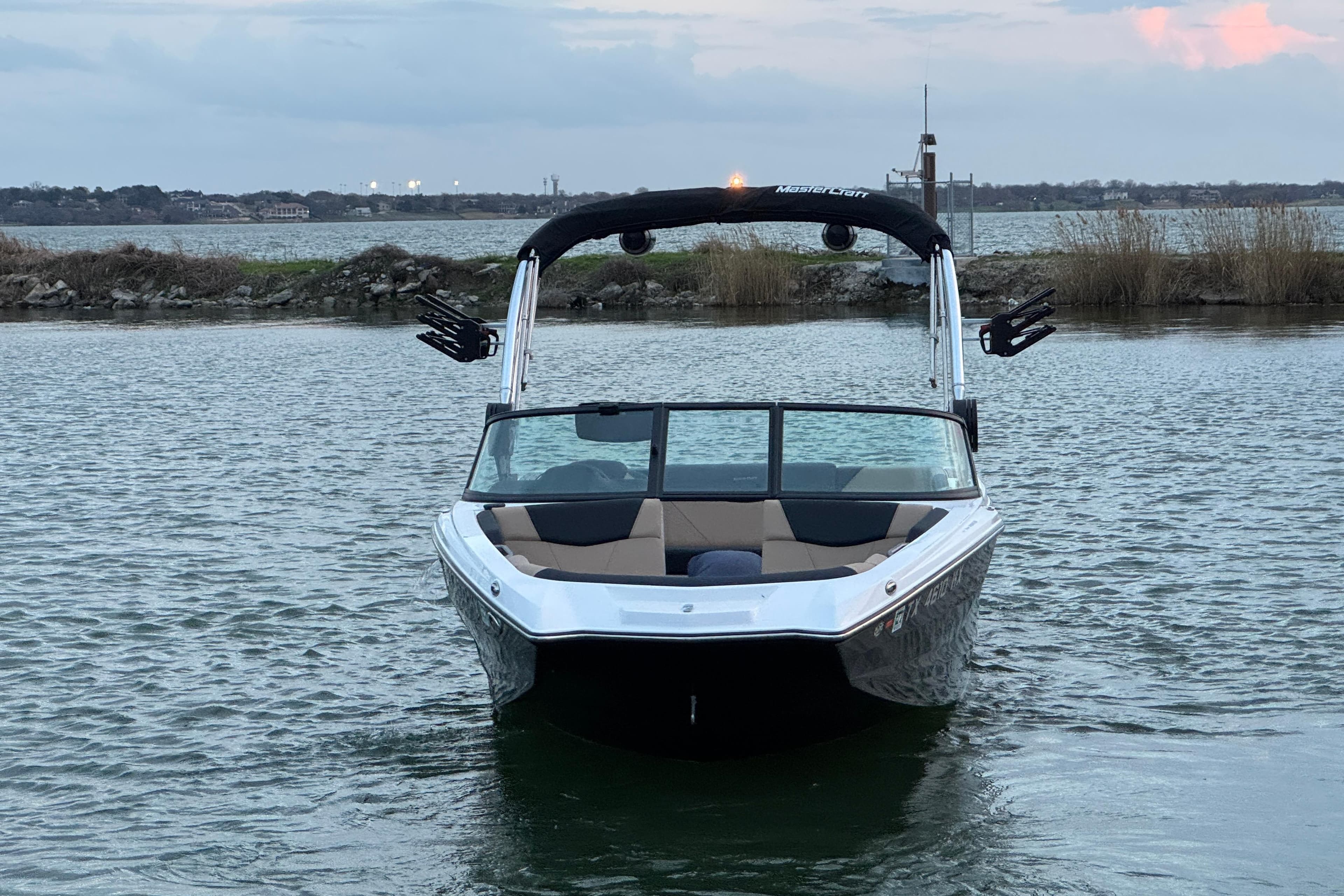 2023 MasterCraft NXT22 boat on calm water at sunset.