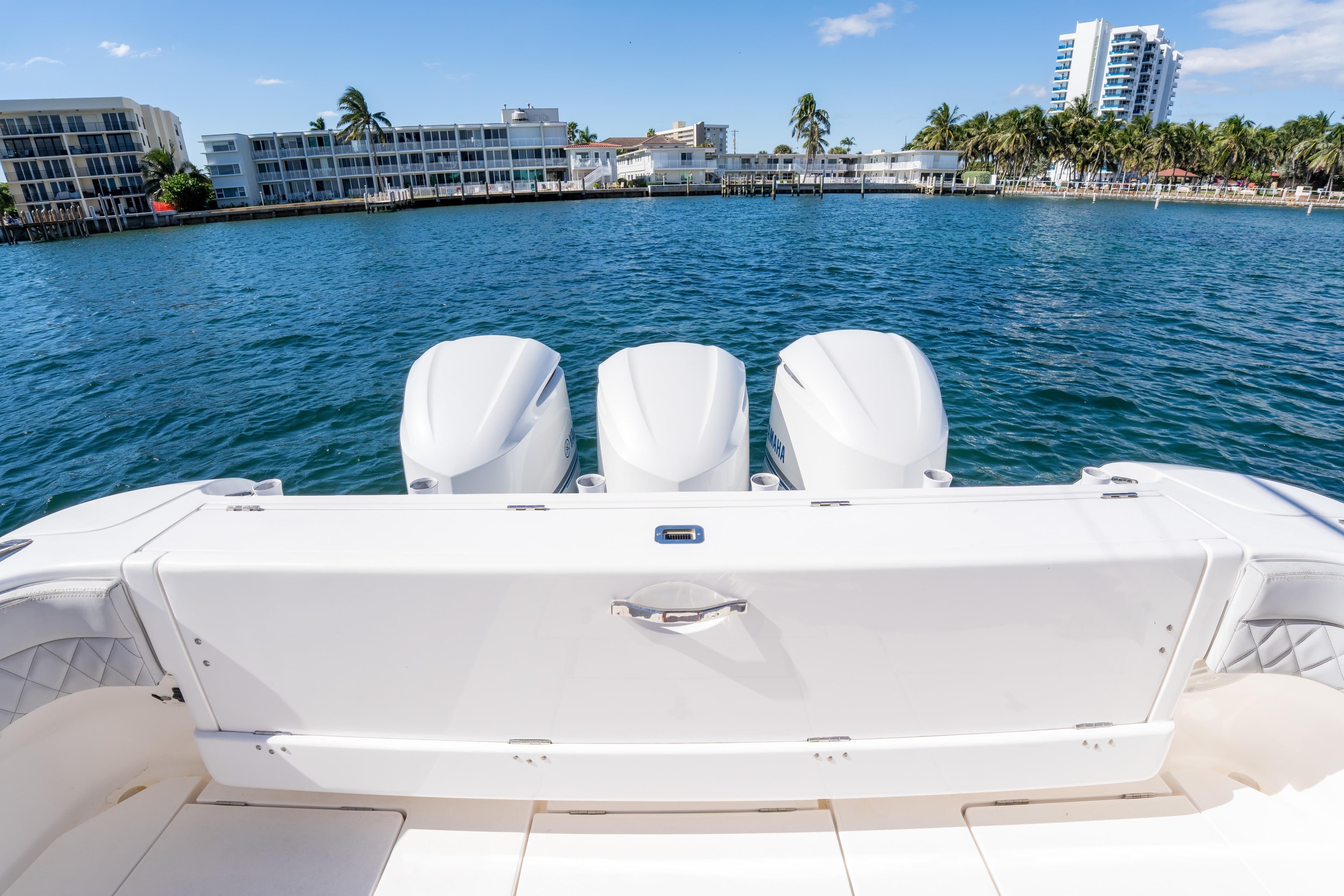 2019 Intrepid 407 Cuddy boat with triple engines on a sunny waterfront.