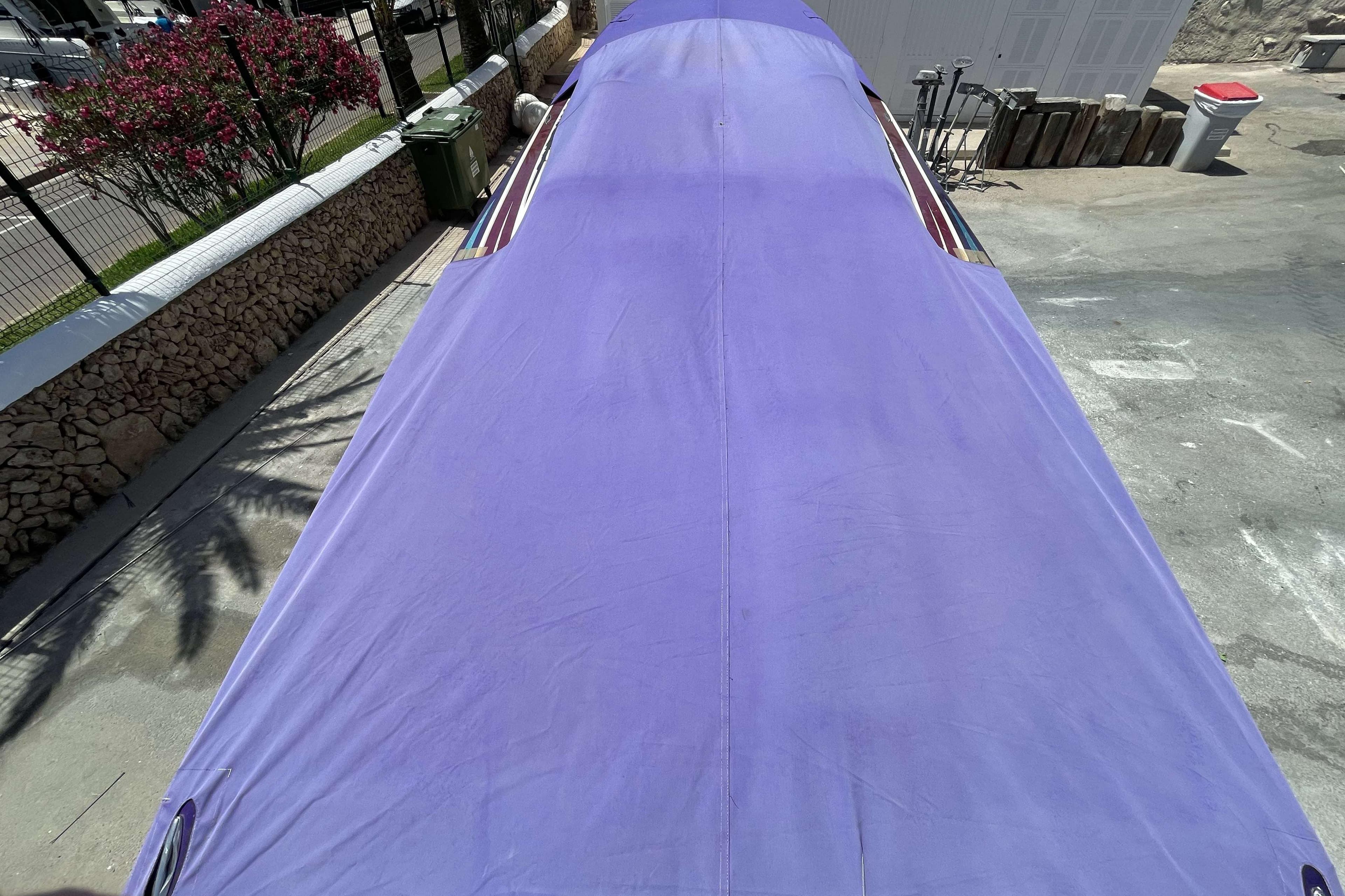 Covered 2004 Cigarette 36' Gladiator boat with purple tarp in outdoor setting.