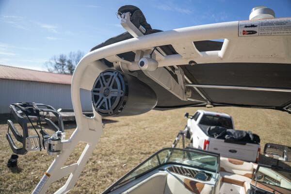 2017 Correct Craft Super Air Nautique GS boat with speaker and canopy, parked near a truck.