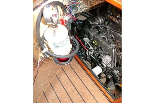Engine compartment of 1999 Island Packet 45 sailboat, featuring mechanical components and fire extinguisher.