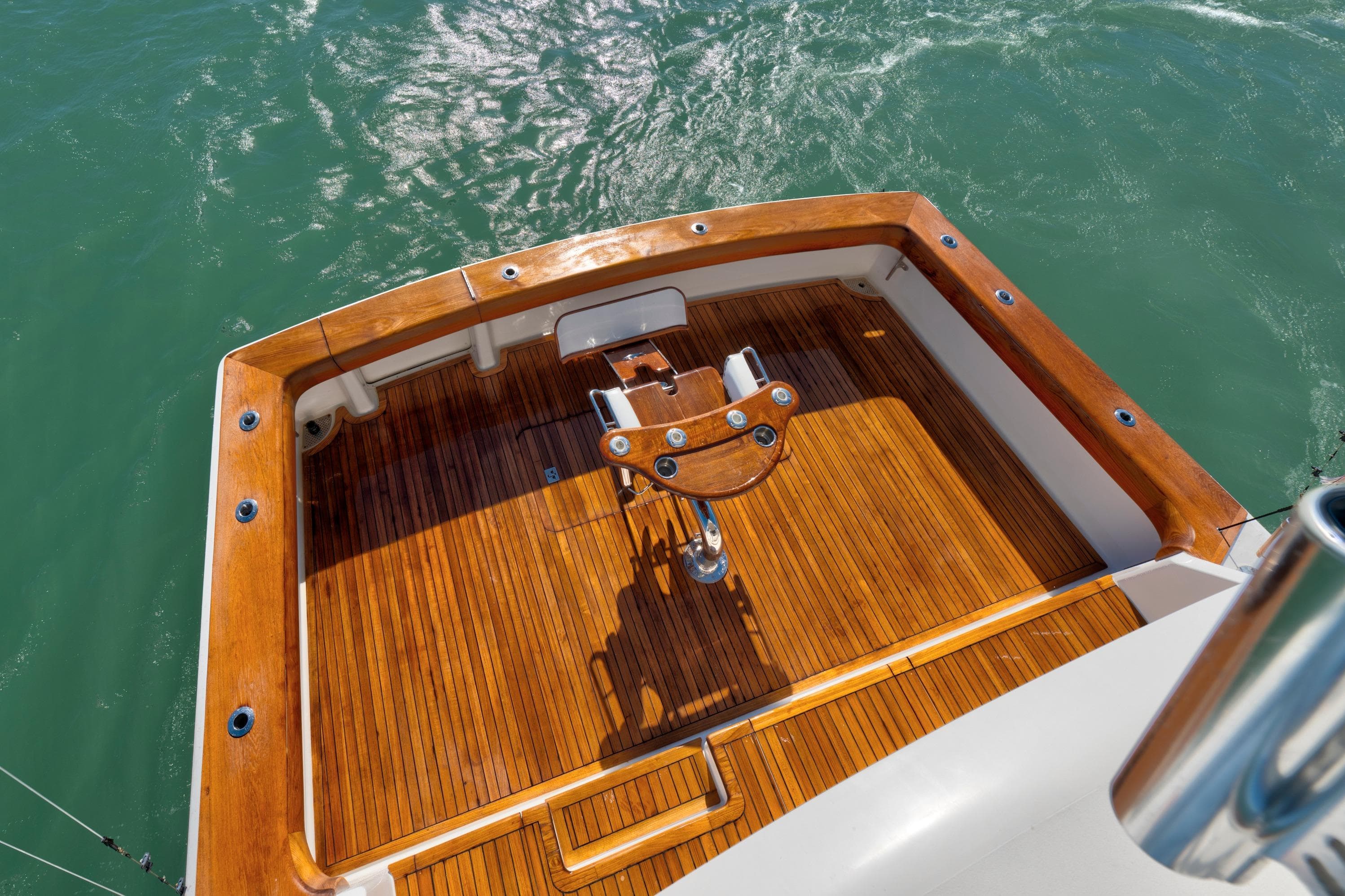 2002 Viking Convertible yacht with polished wooden deck and fishing chair on calm water.