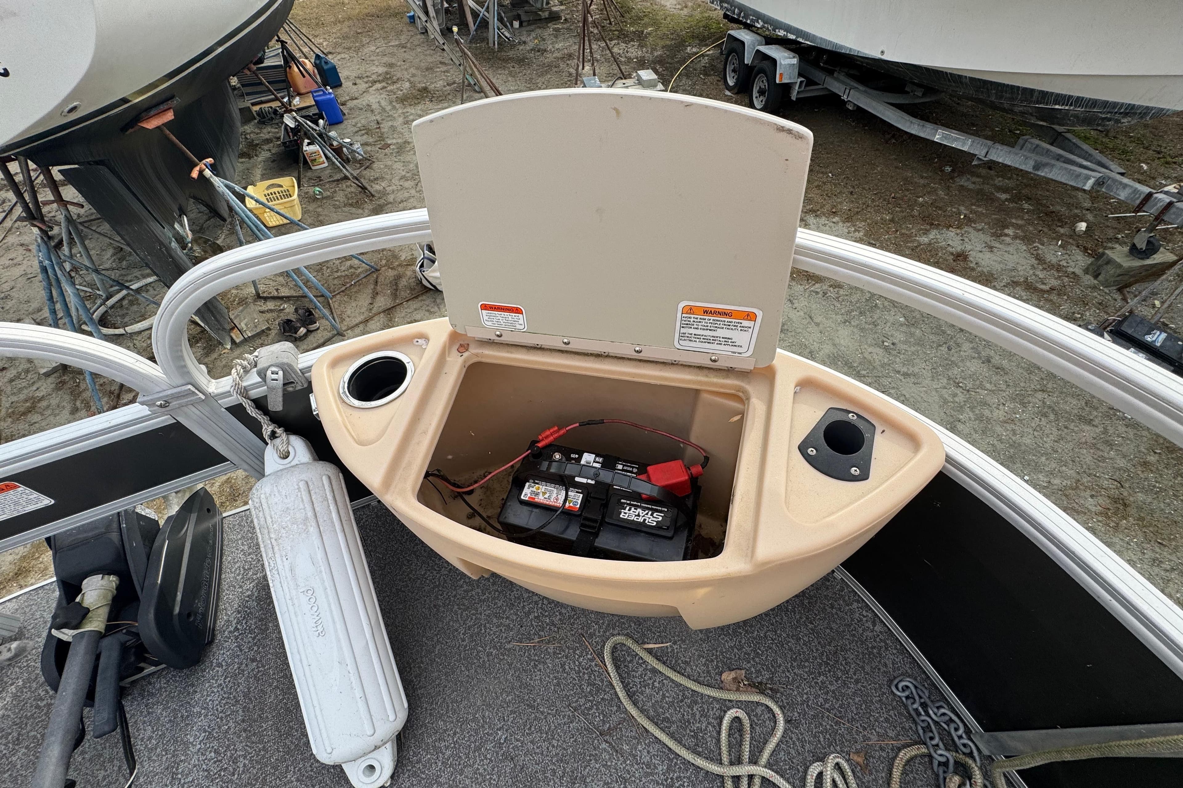 Open storage compartment on 2017 Sun Tracker Party Barge 22 Tritoon, showing battery and cup holders.