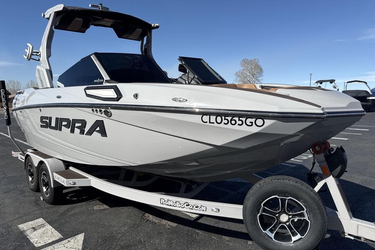 2024 Supra SV boat on trailer, sleek design, parked outdoors under clear sky.