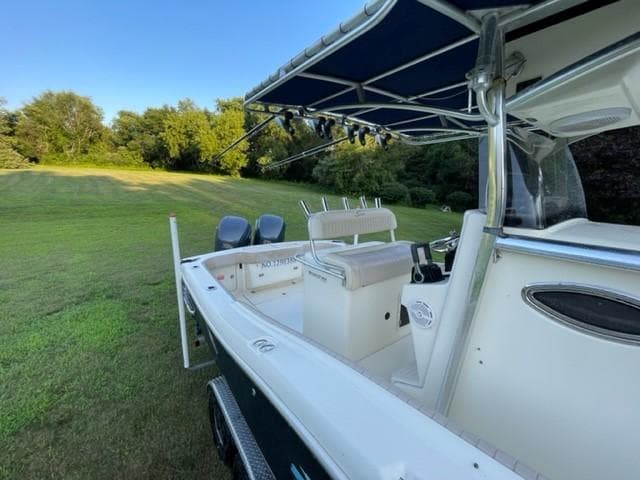 2003 Scout 280 Sportfish boat with canopy, parked on grassy field.