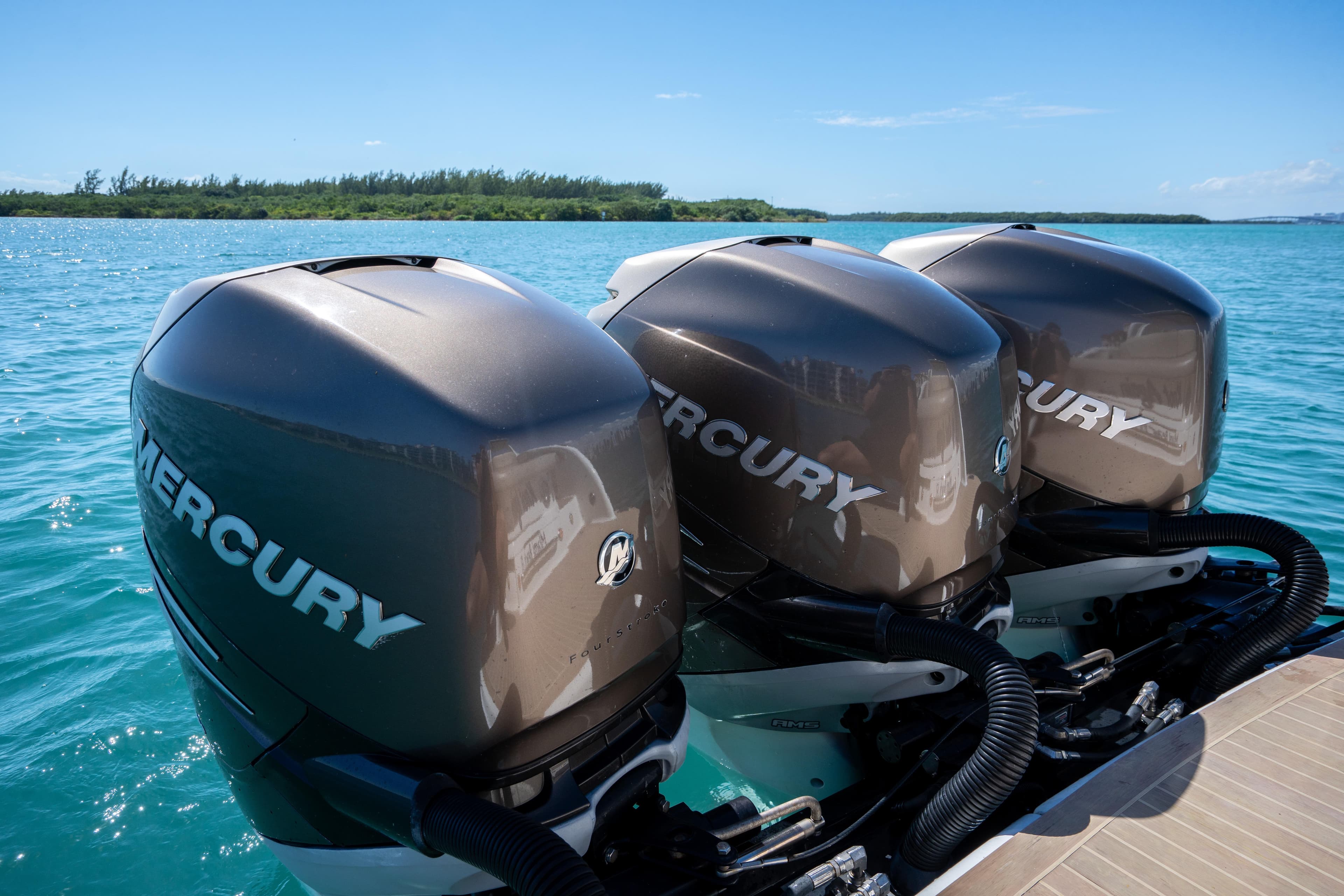 Triple Mercury outboard engines on a 2018 Formula 350 Crossover Bowrider OB in clear blue waters.