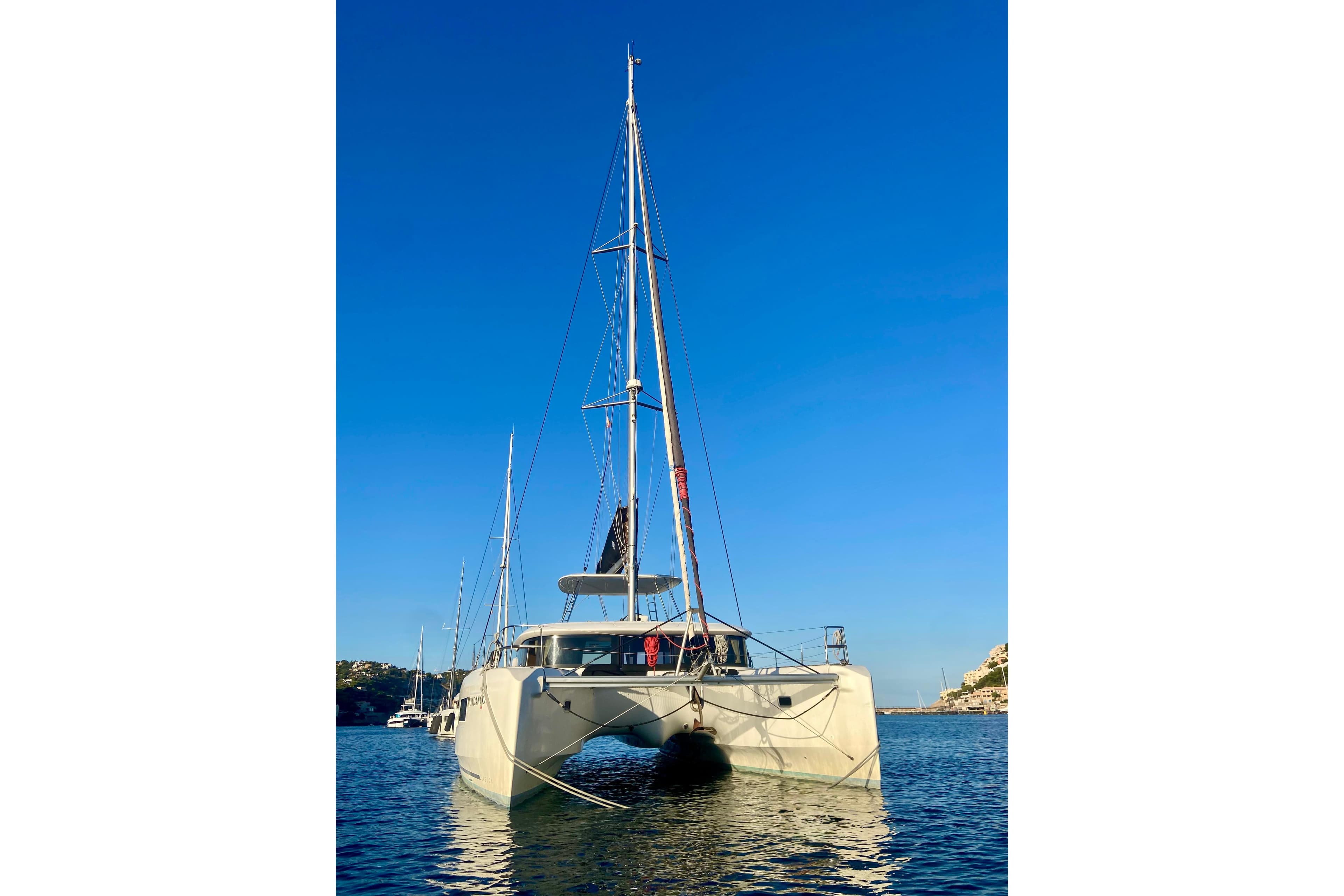 2020 Lagoon 46 catamaran anchored on calm water under clear blue sky.