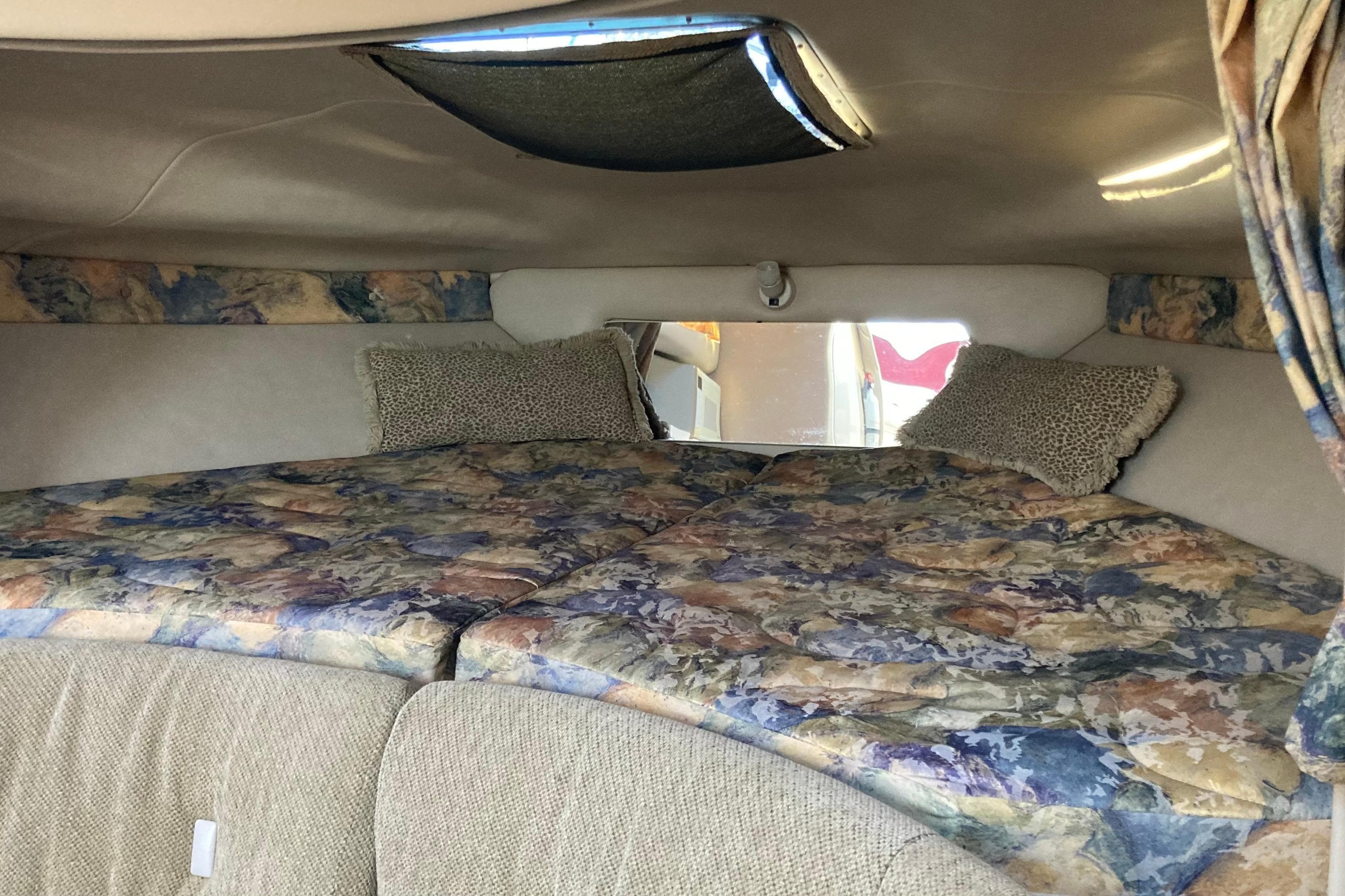 Interior cabin of 1999 Chaparral Signature 29 boat with patterned bedding and pillows.