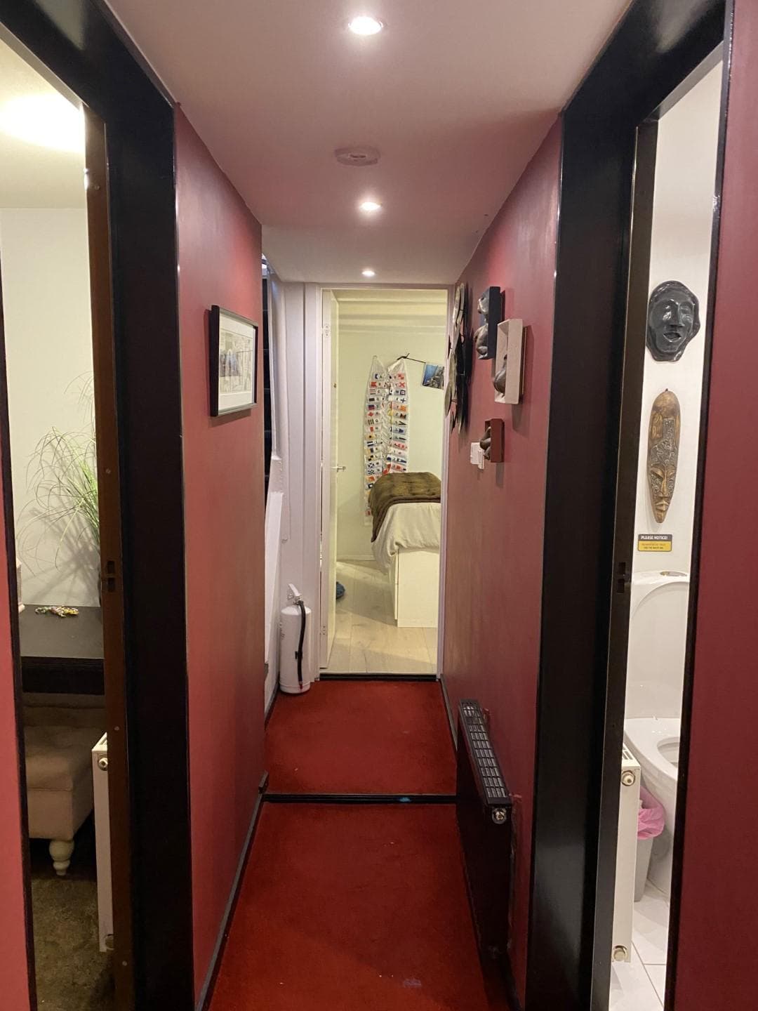Narrow hallway inside a 1896 Classic 29m Converted Icebreaker, featuring red walls and modern decor.