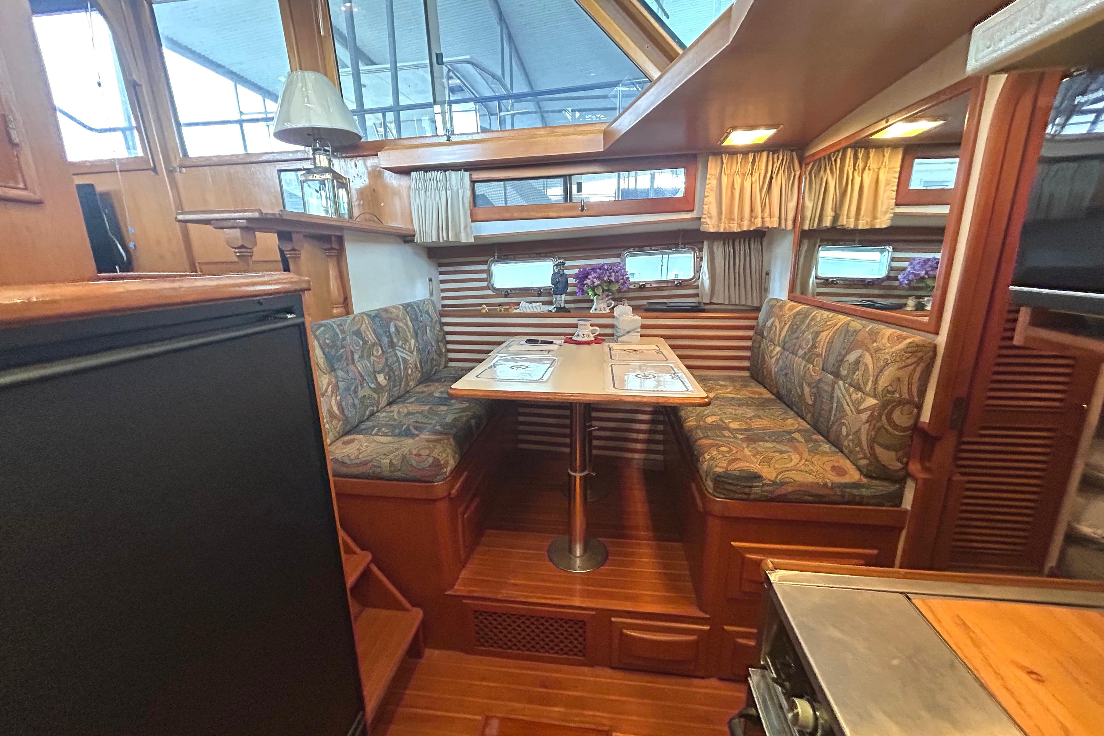 Interior of 1988 CHB Ponderosa Motor Yacht with cozy dining area and wooden finishes.